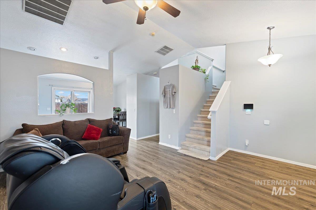 Living area with wood finished floors, stairway, a ceiling fan, vaulted ceiling, and recessed lighting