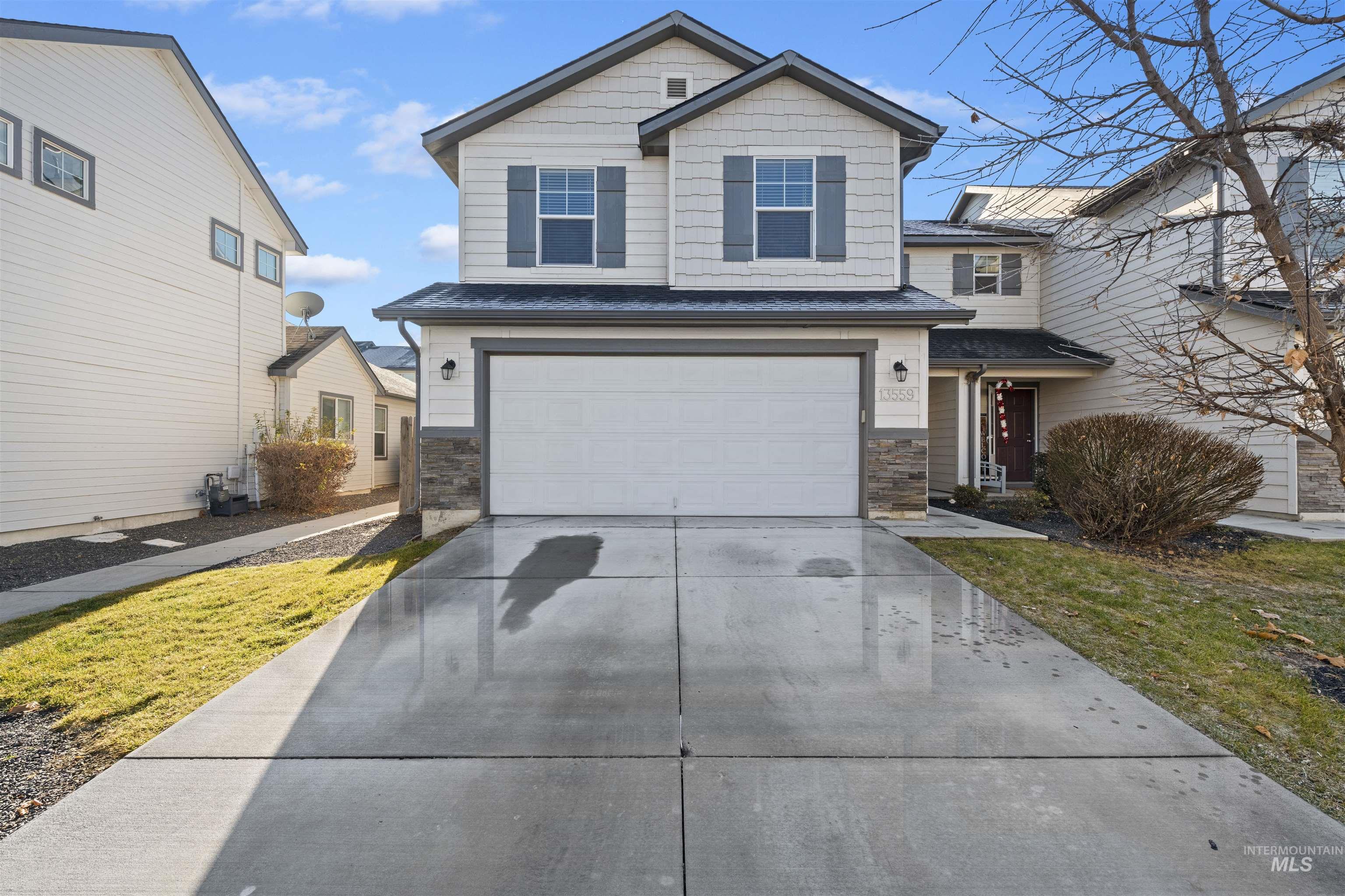 View of front of home with driveway, a garage, and stone siding