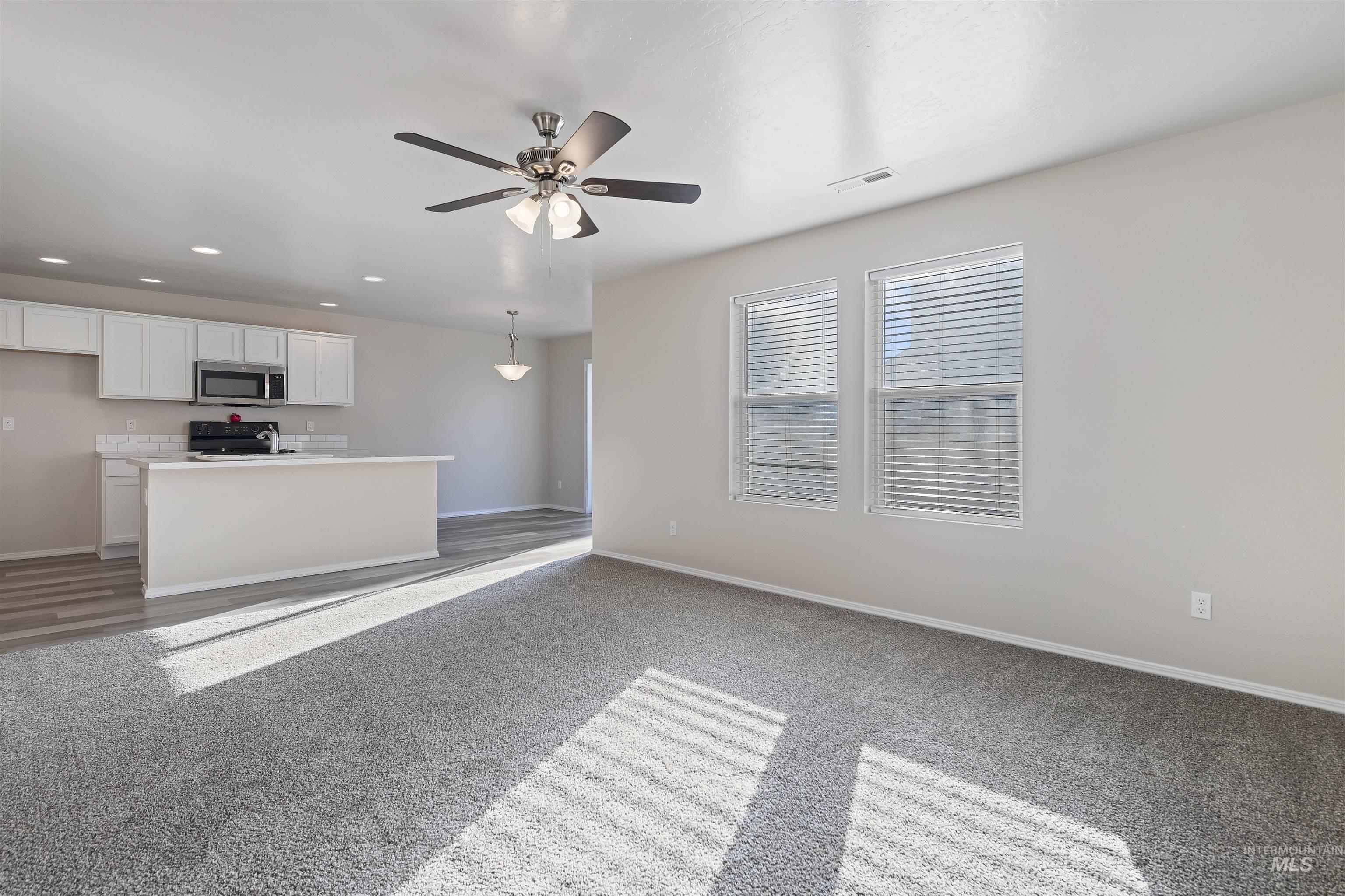 Unfurnished living room with a ceiling fan, recessed lighting, and light carpet