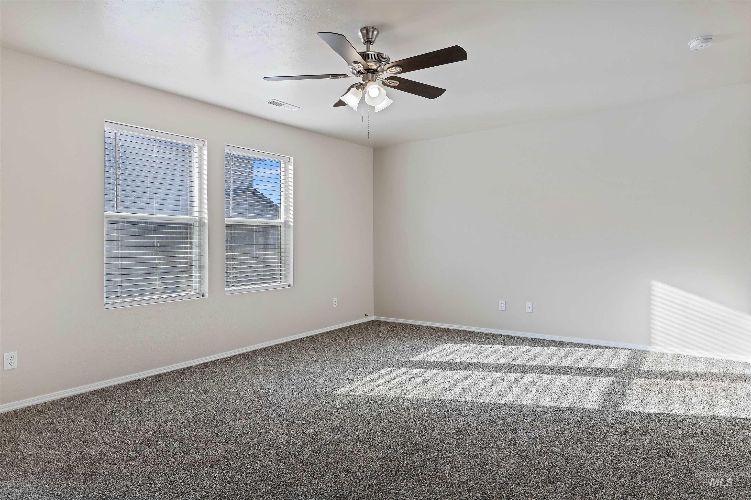 Carpeted spare room featuring baseboards and a ceiling fan