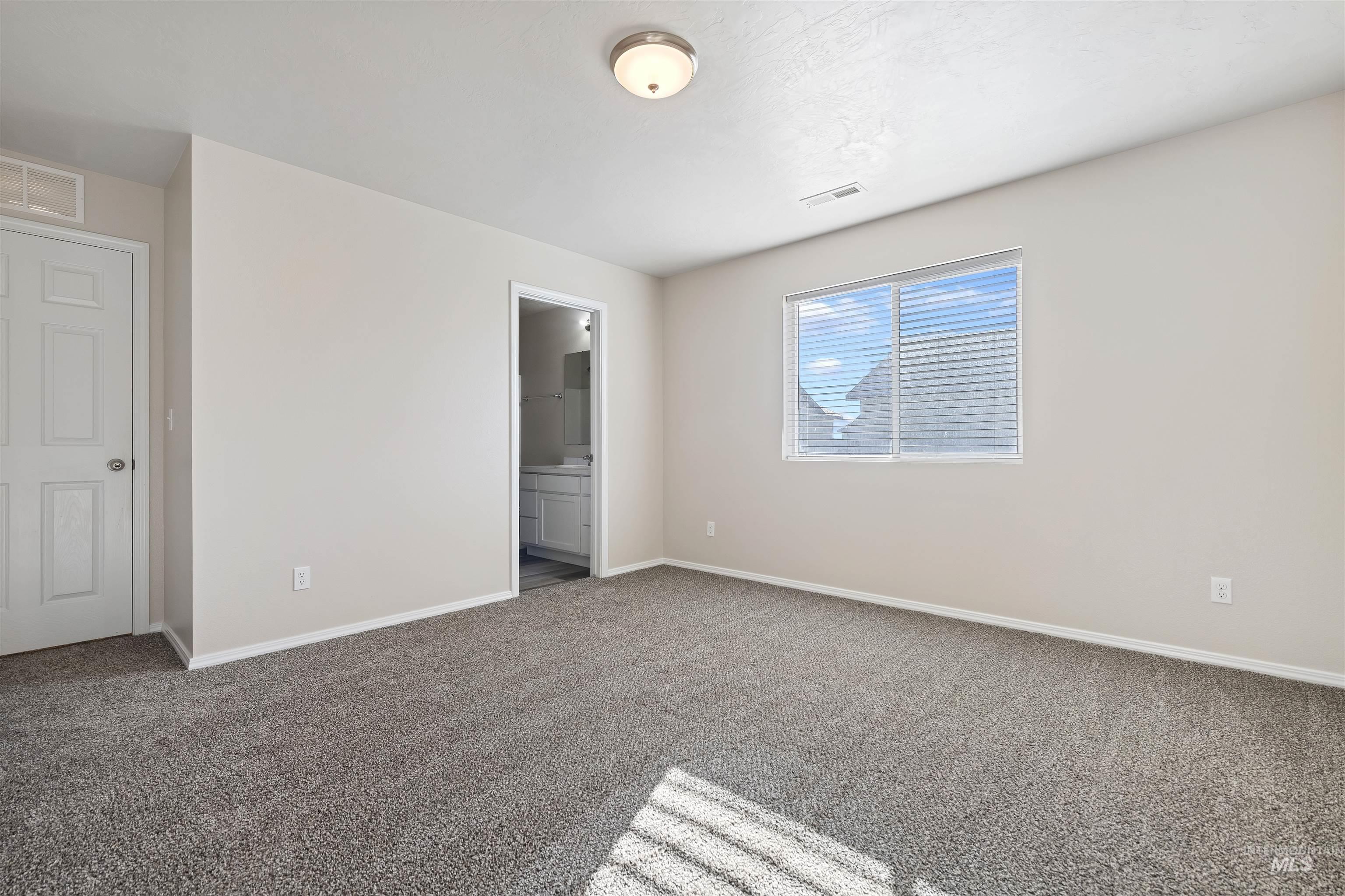 Unfurnished bedroom featuring connected bathroom and carpet flooring