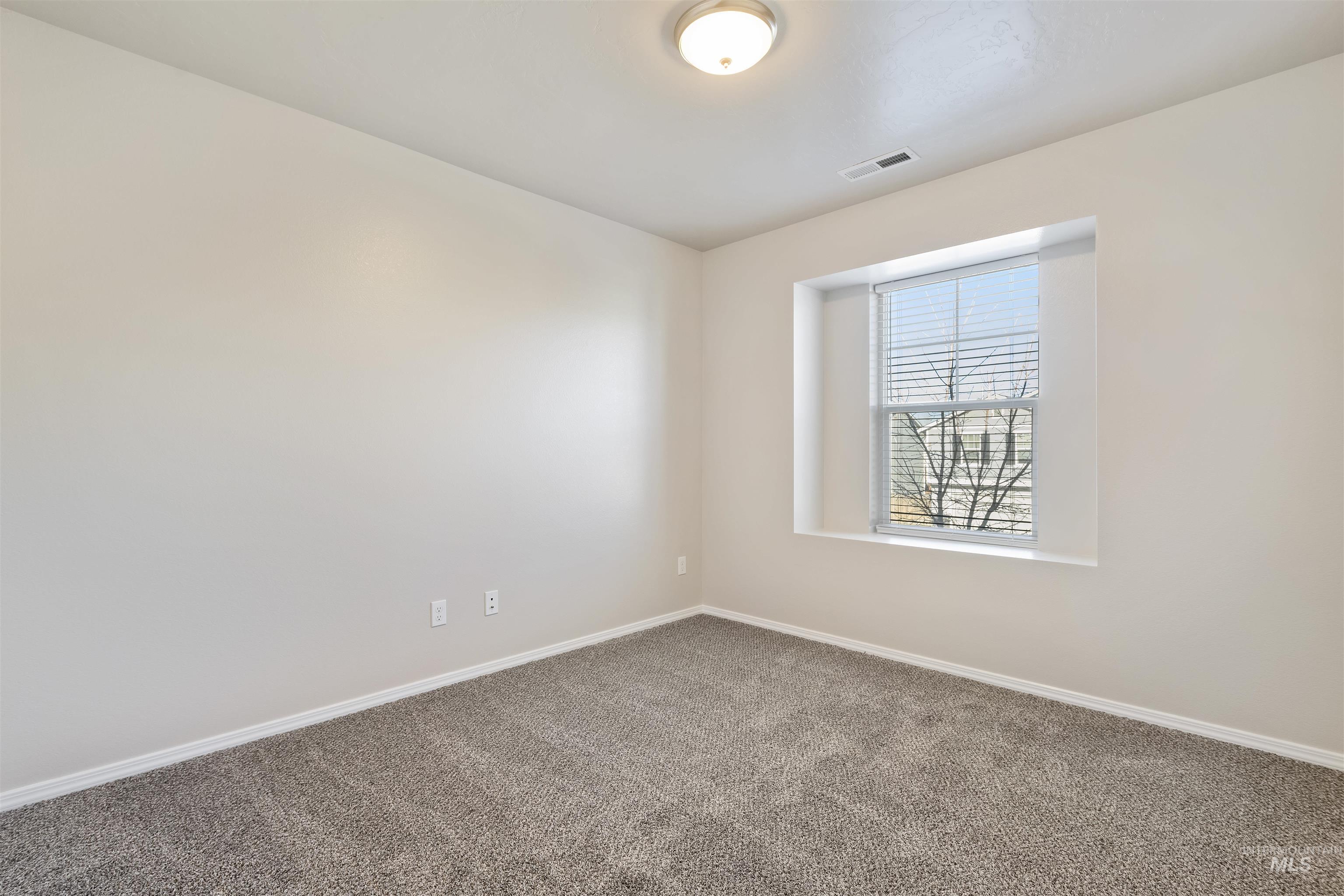 Carpeted spare room featuring baseboards