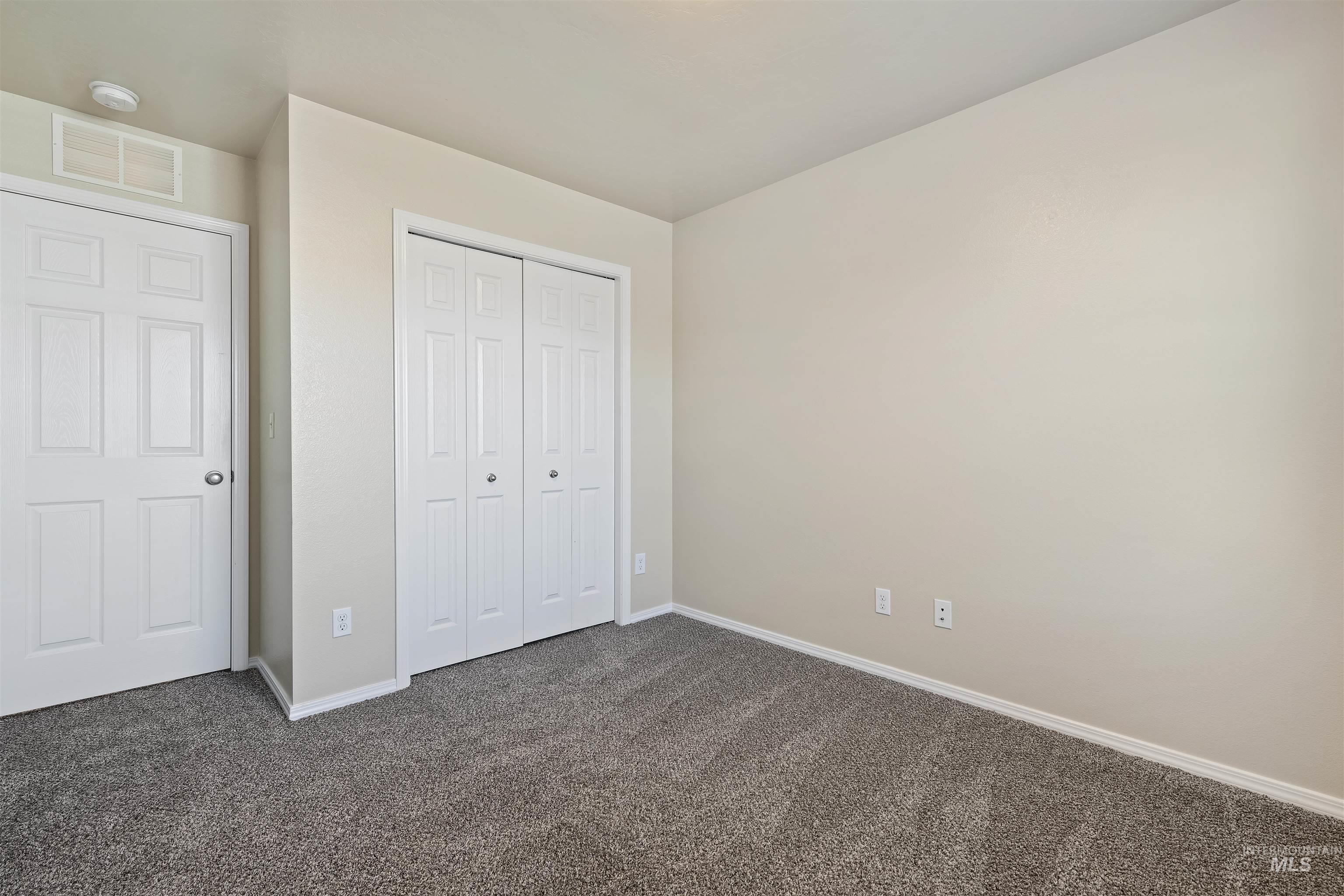 Unfurnished bedroom with dark carpet and a closet