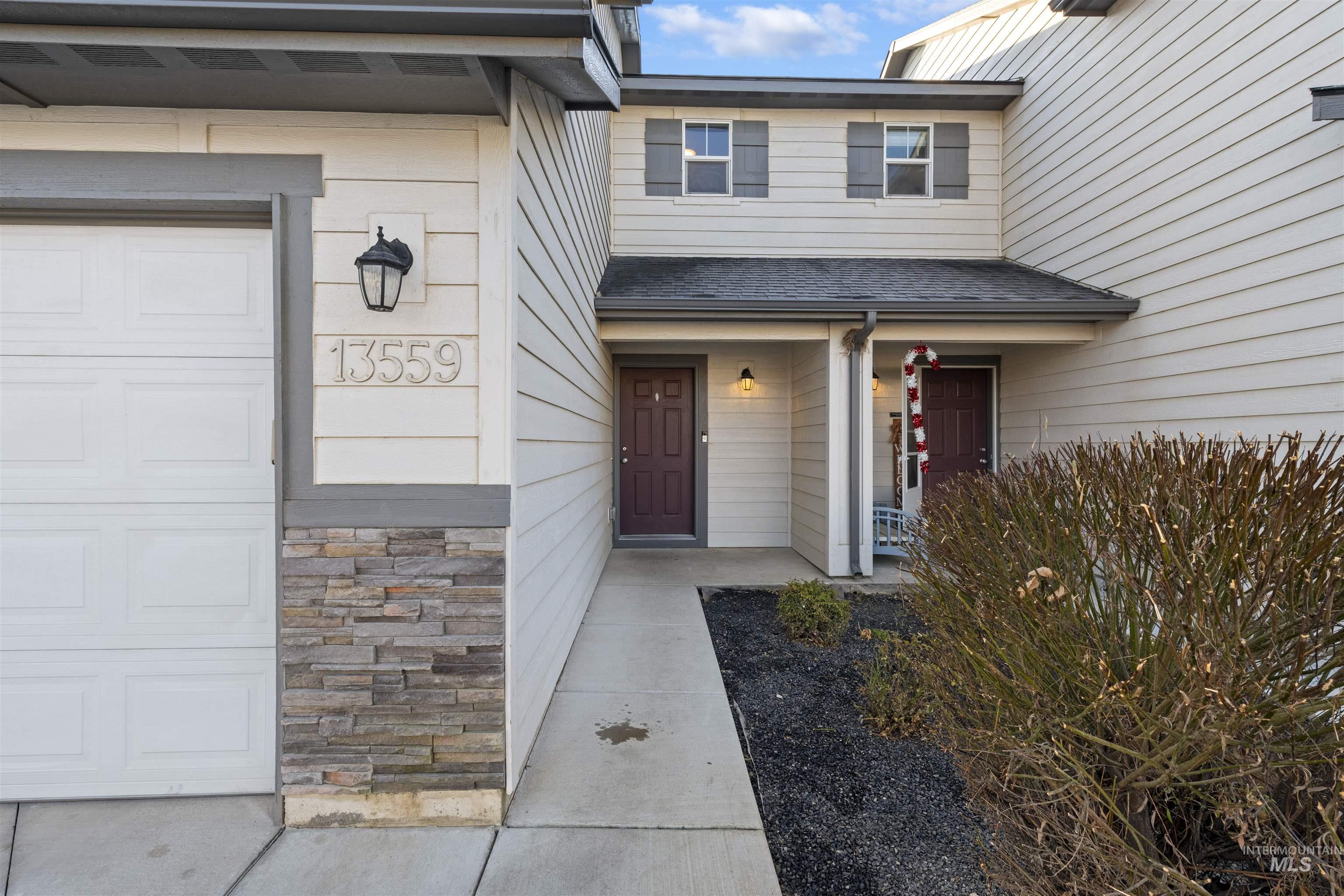 Entrance to property with covered porch, stone siding, and a garage