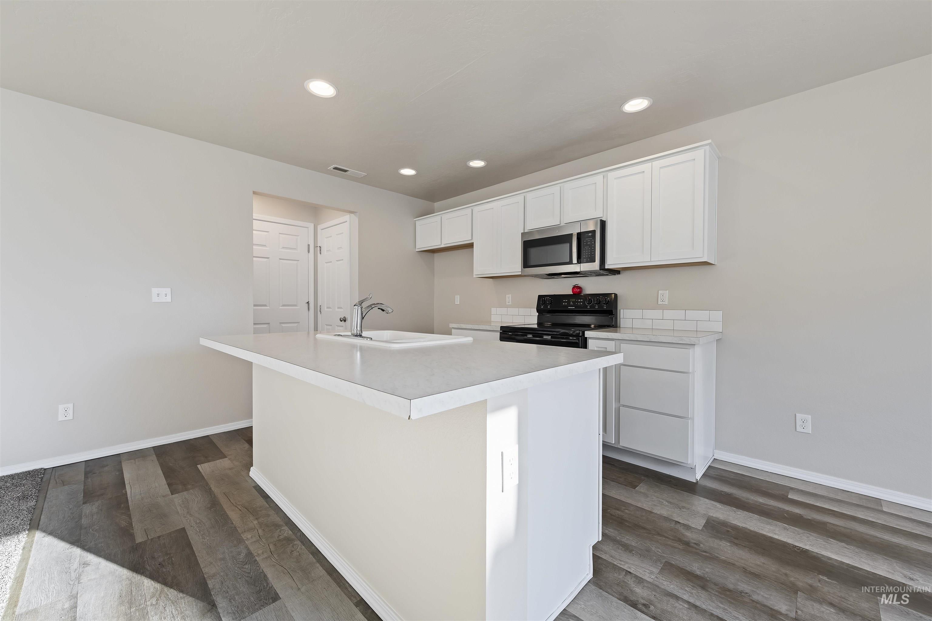 Kitchen with white cabinetry, black range with electric stovetop, light countertops, dark wood finished floors, and recessed lighting