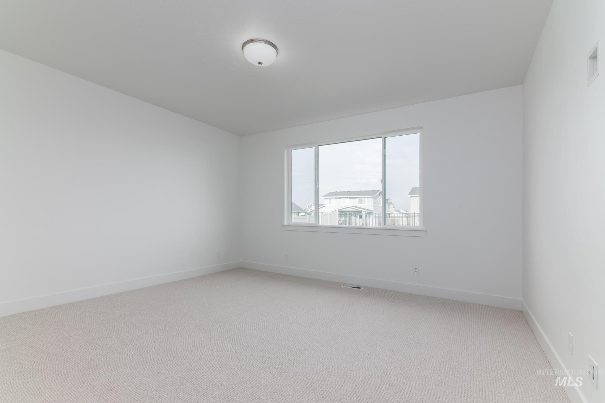 Empty room with light colored carpet and baseboards