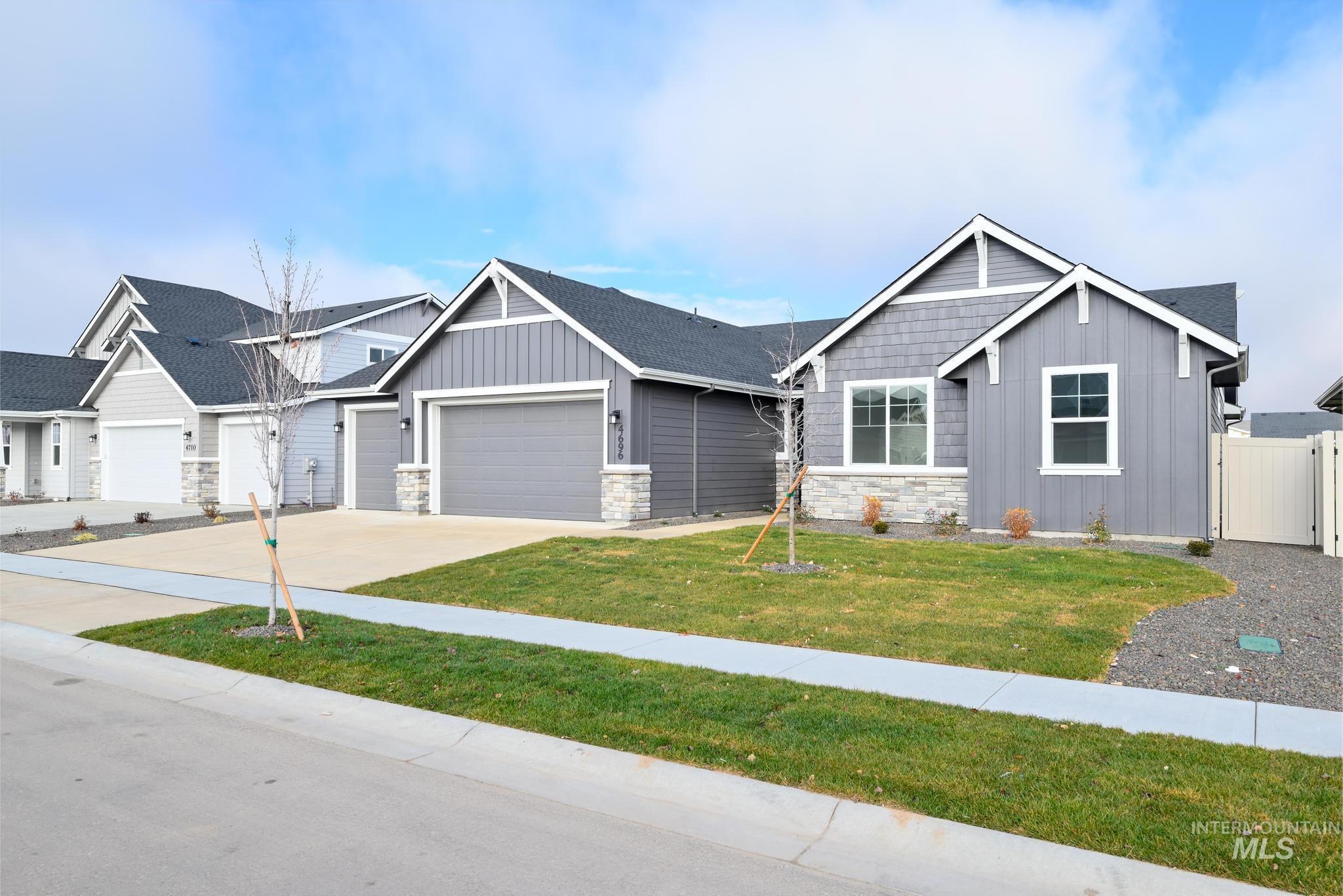 Craftsman inspired home with board and batten siding, stone siding, concrete driveway, and a garage