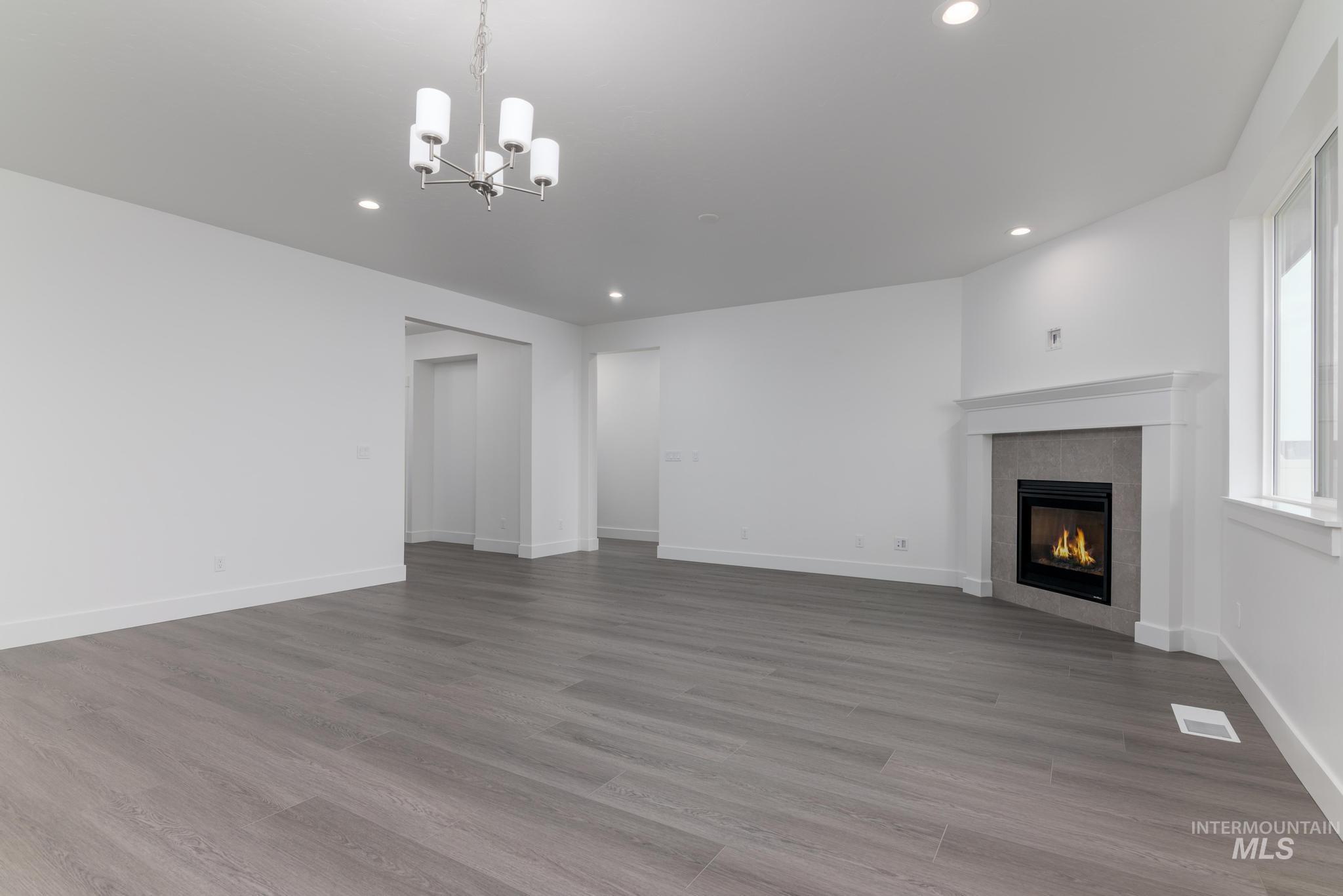 Unfurnished living room with a chandelier, a tile fireplace, light wood-style floors, and recessed lighting