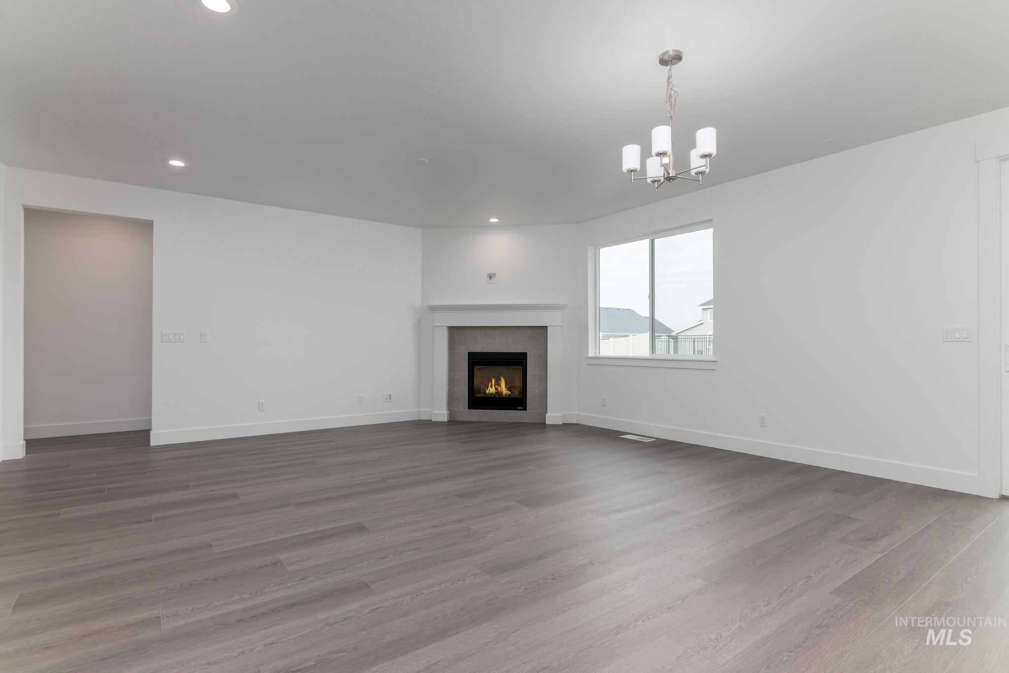 Unfurnished living room with light wood-style floors, a fireplace, recessed lighting, and a chandelier