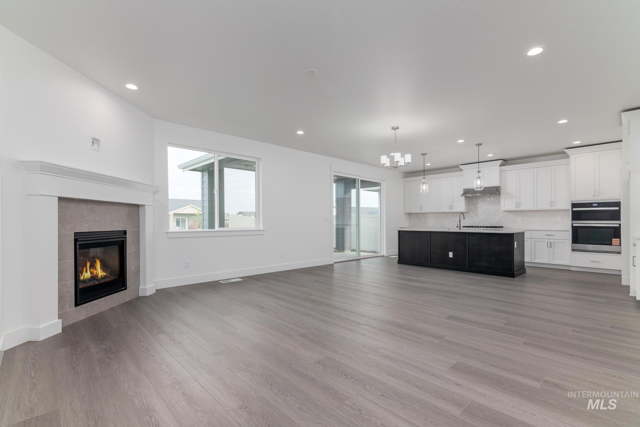 Unfurnished living room with a chandelier, recessed lighting, light wood-type flooring, and a fireplace