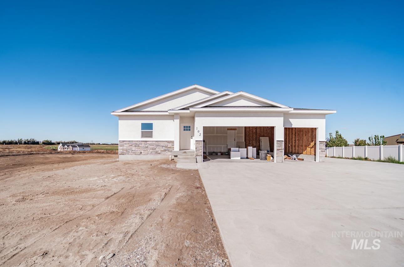 View of front of home with stone siding, driveway, stucco siding, an attached garage, and a porch