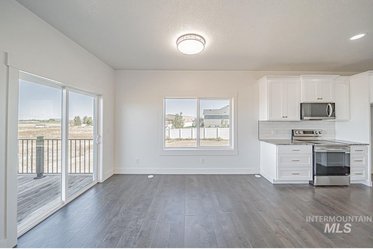 Kitchen featuring white cabinetry, appliances with stainless steel finishes, tasteful backsplash, and healthy amount of natural light