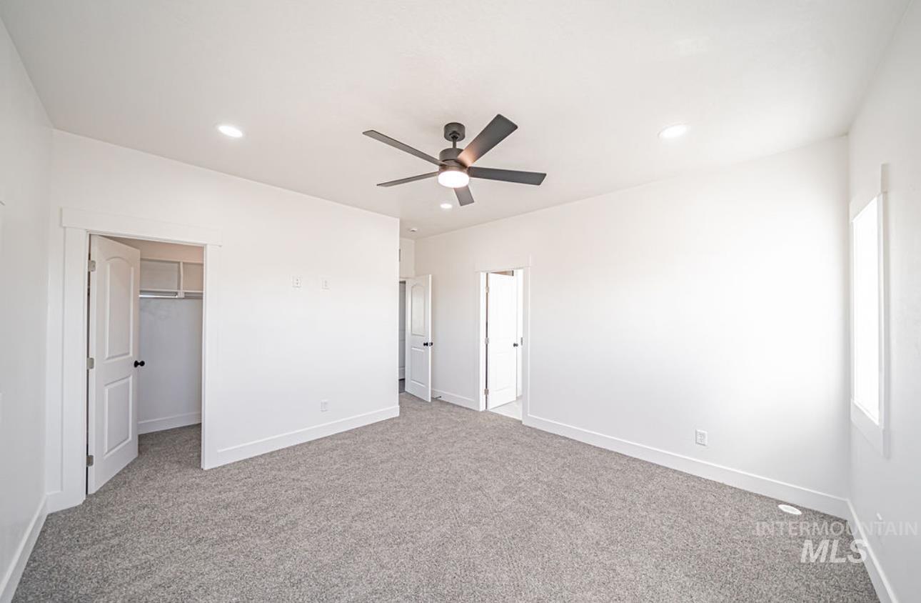 Unfurnished bedroom featuring a walk in closet, light colored carpet, a ceiling fan, and recessed lighting