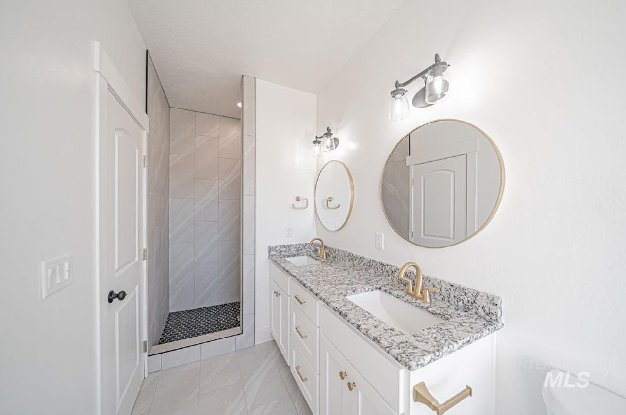 Full bathroom with double vanity and tiled shower