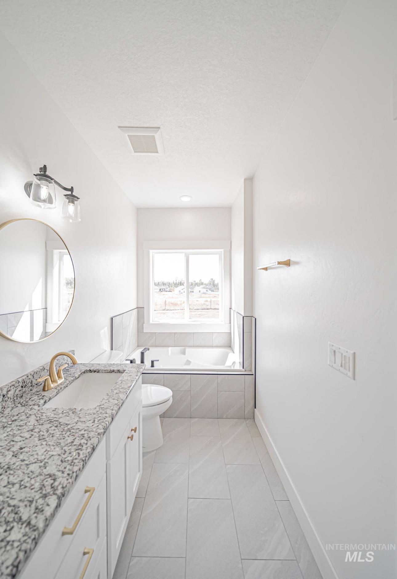 Bathroom with a bath, vanity, light tile patterned floors, and a textured ceiling