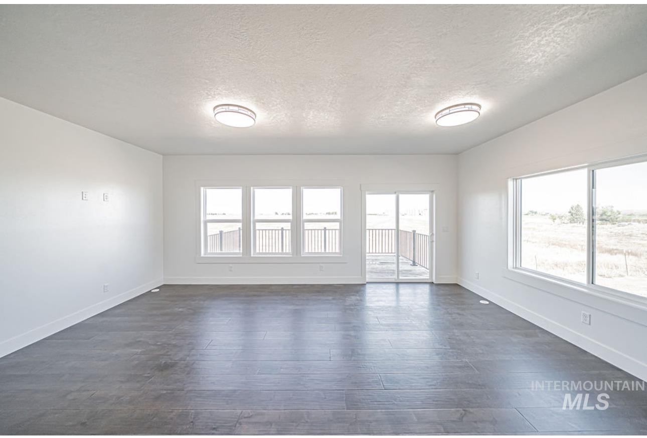 Unfurnished room featuring a textured ceiling, plenty of natural light, and dark wood-style floors