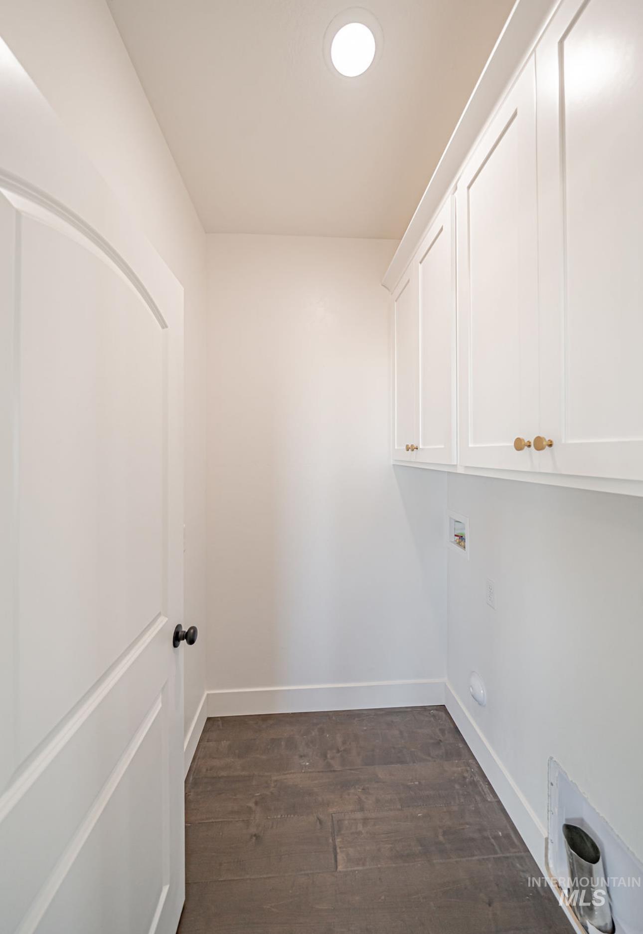 Laundry area featuring dark wood finished floors, hookup for a washing machine, and cabinet space