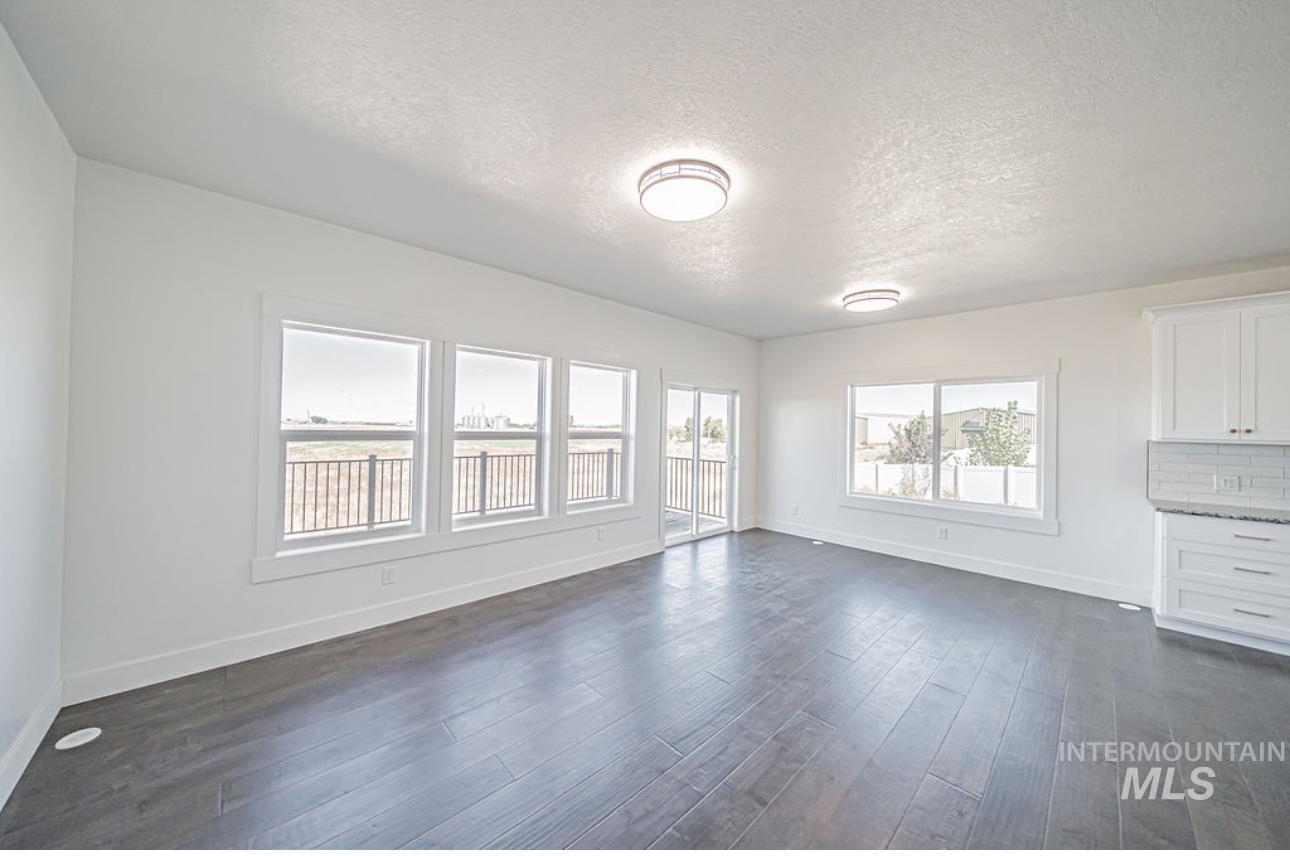 Unfurnished living room with a textured ceiling and dark wood-type flooring