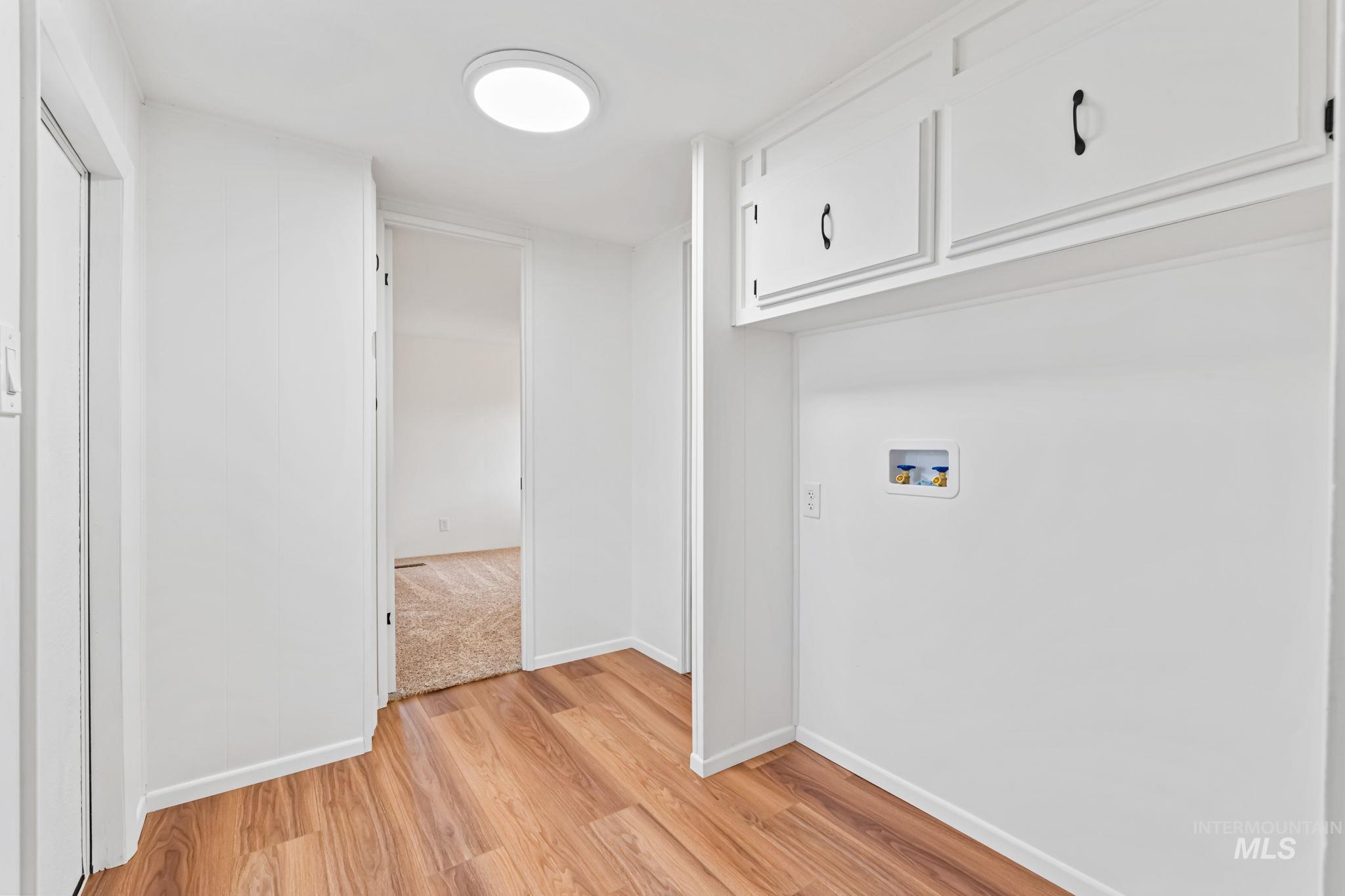 Laundry area with light wood-style flooring and hookup for a washing machine
