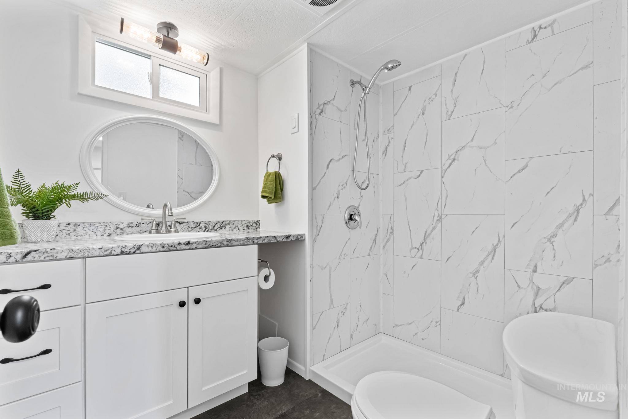 Full bath featuring vanity and a marble finish shower