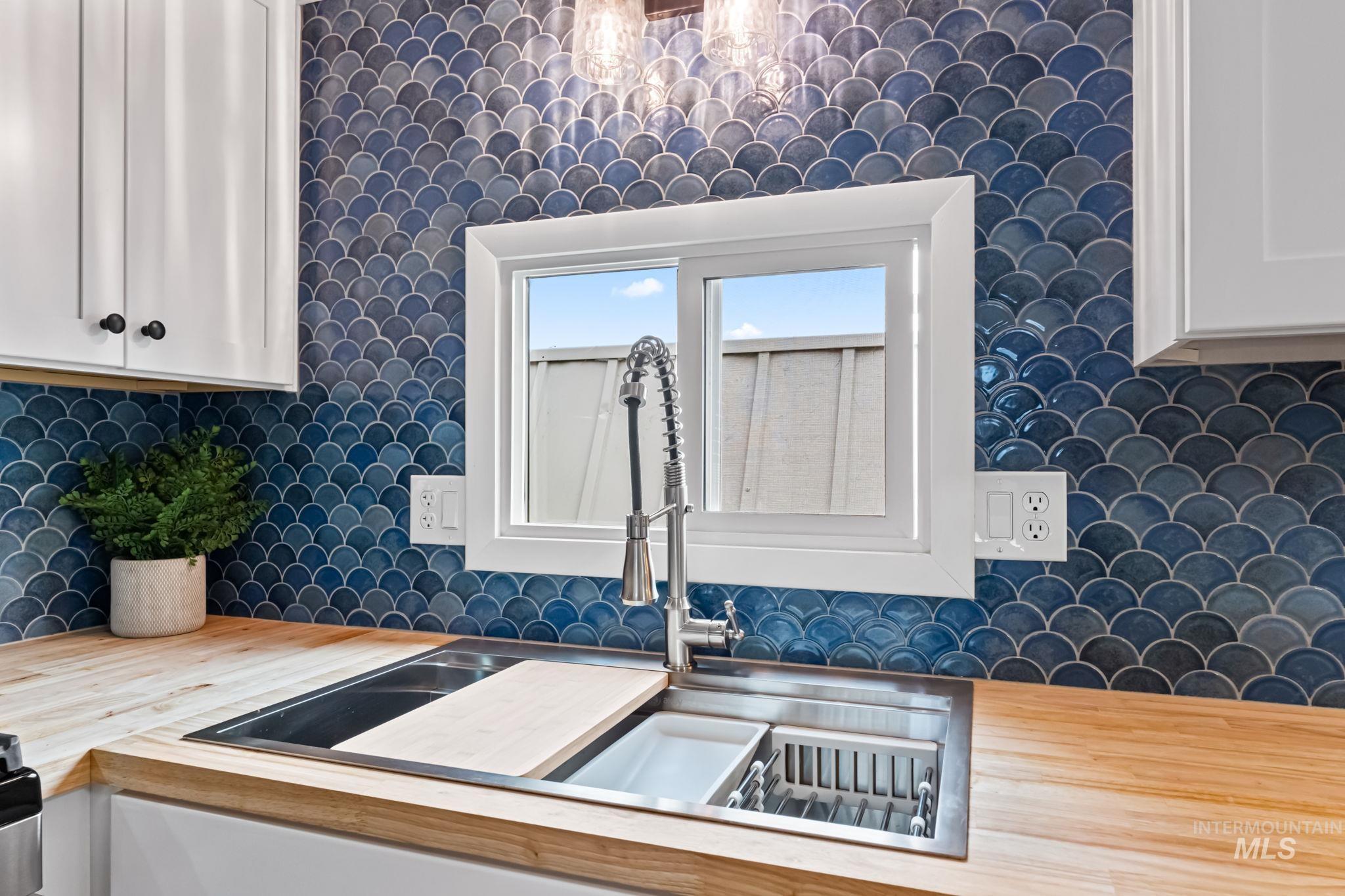 Kitchen view of tasteful backsplash, white cabinetry, and light countertops