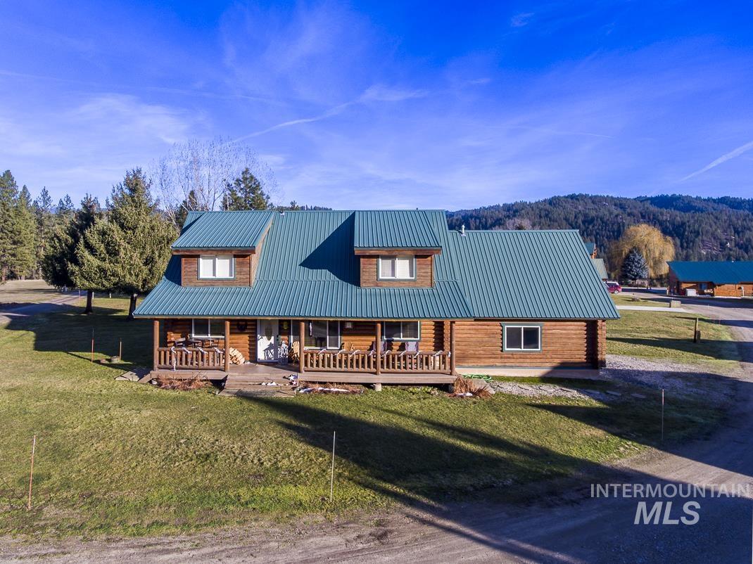 Cabin with a front lawn, a metal roof, covered porch, and log exterior