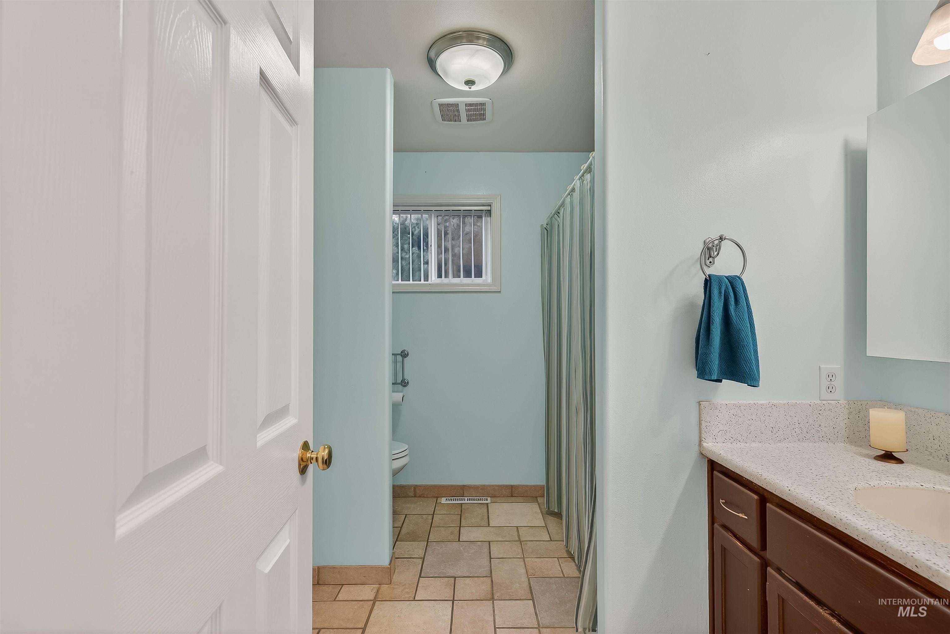 Bathroom featuring a shower with shower curtain, vanity, and stone finish floors