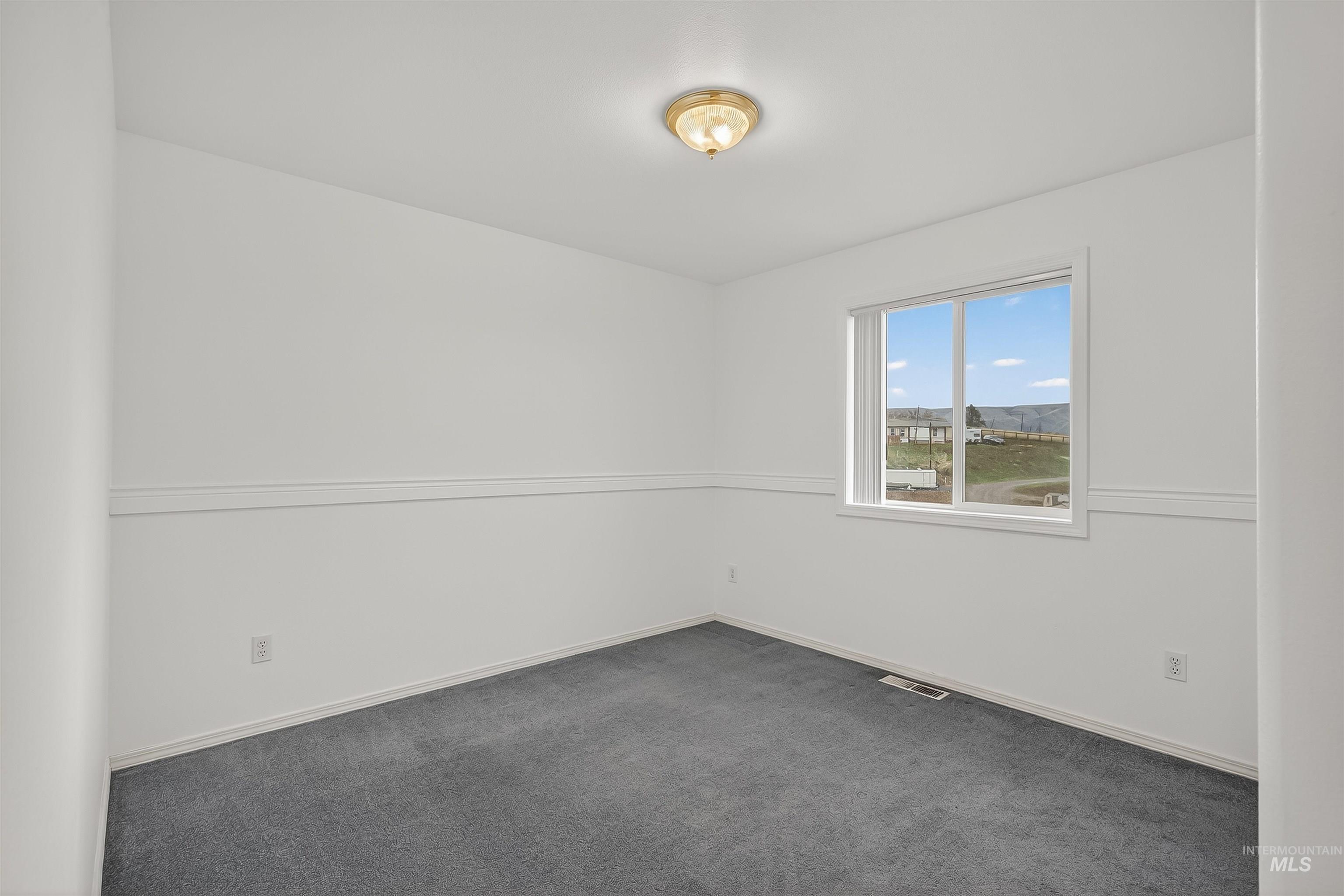 Unfurnished room with dark colored carpet and baseboards