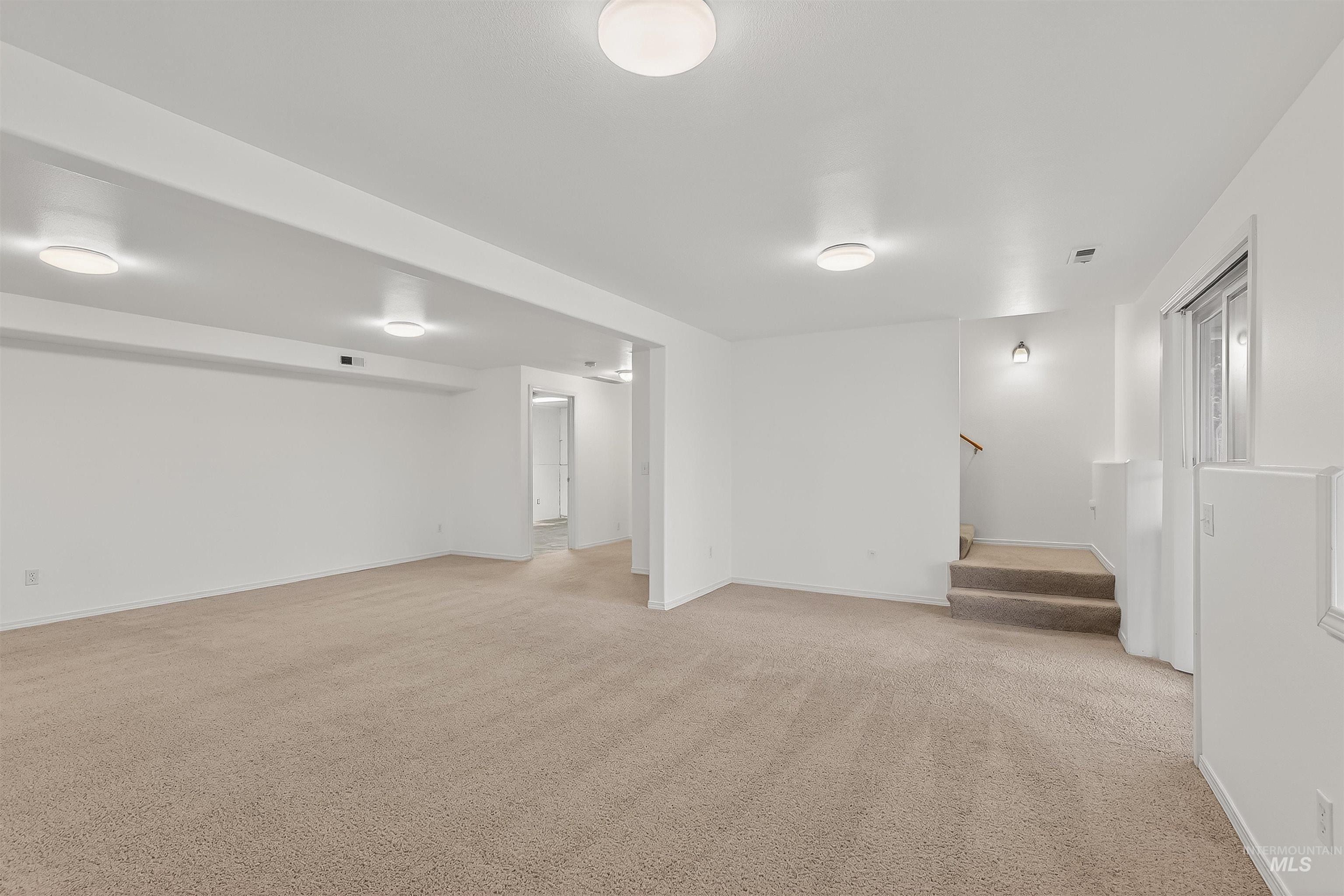 Unfurnished room featuring light carpet and stairs