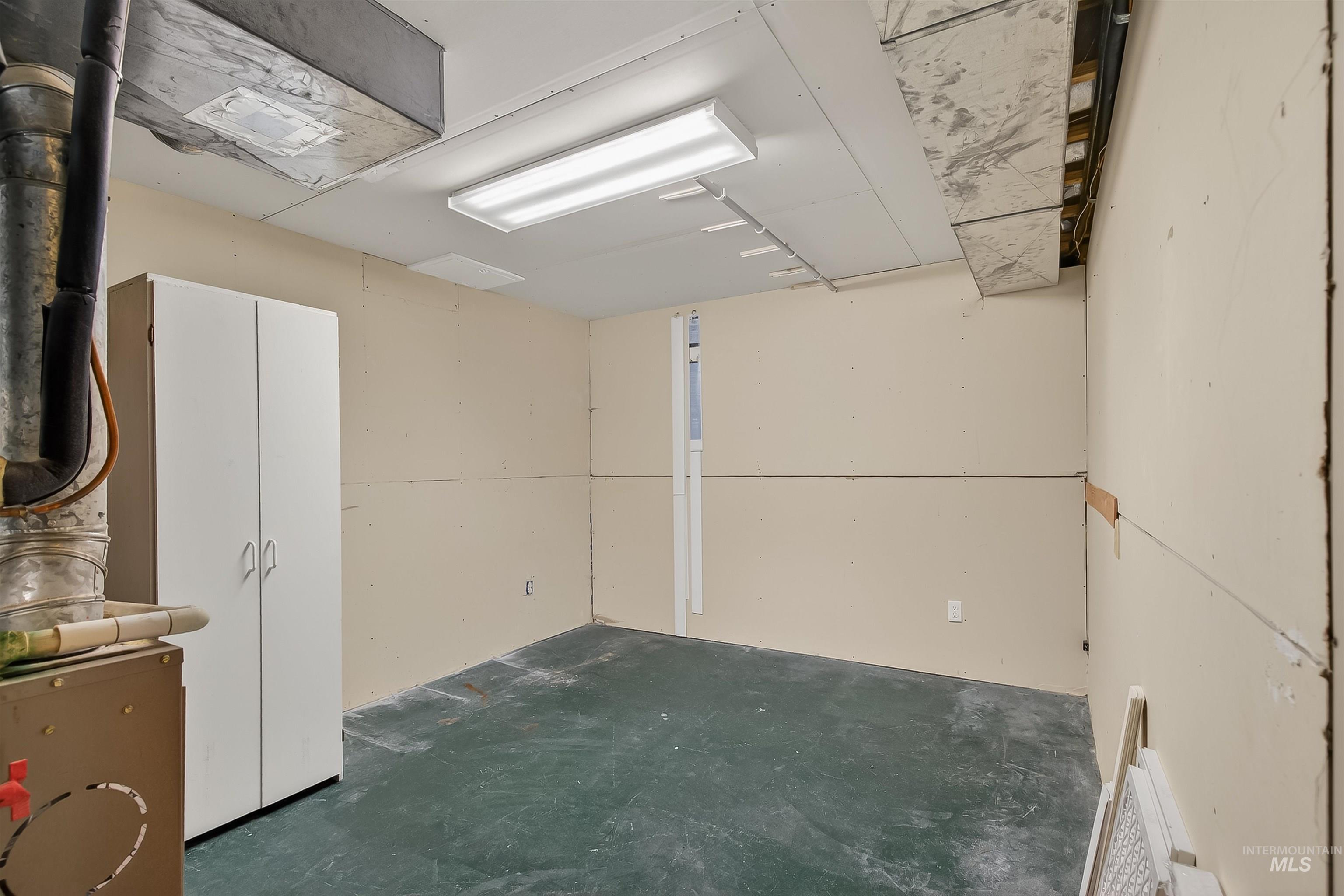 Empty room featuring heating unit and unfinished concrete floors