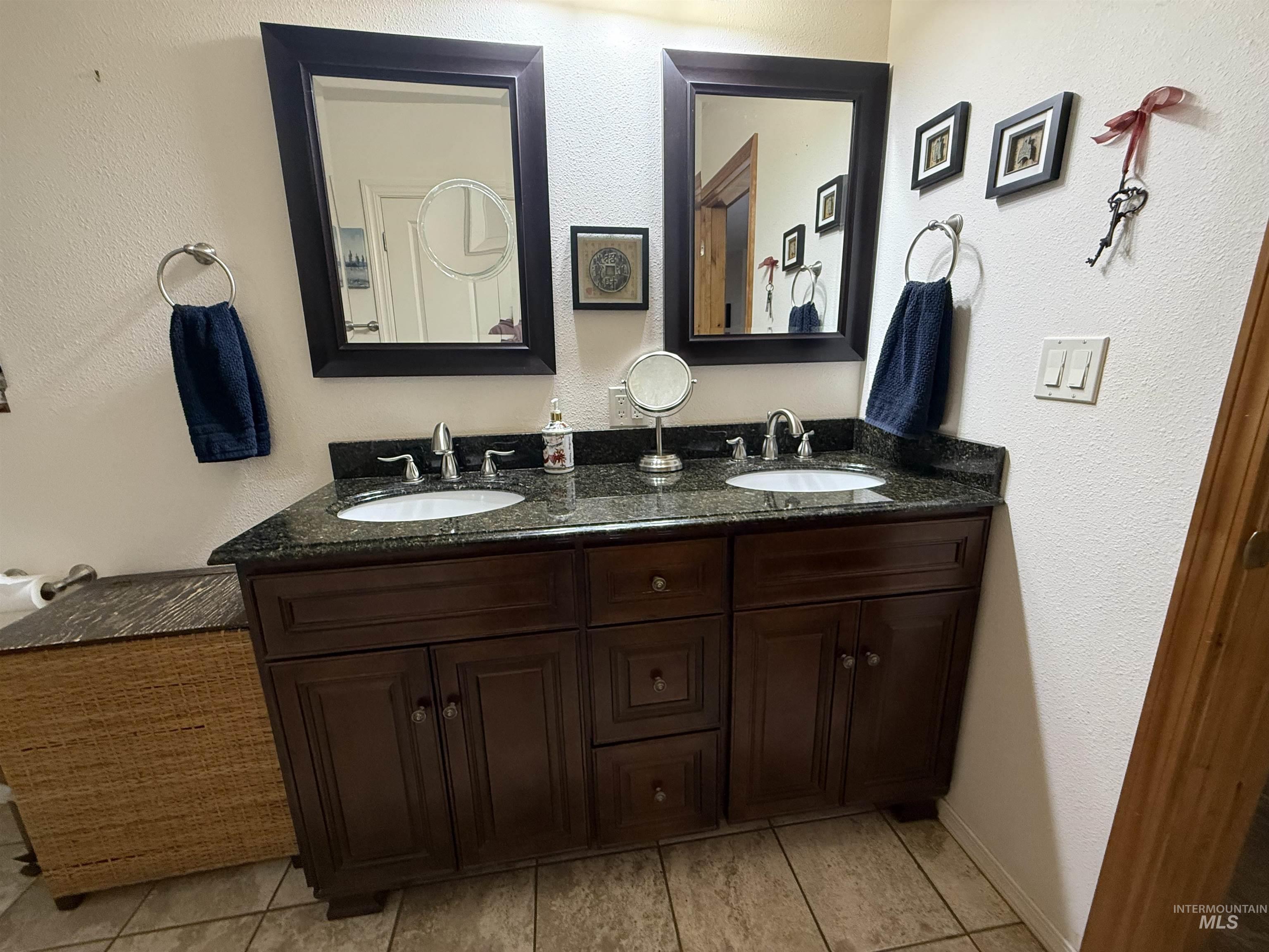 Full bathroom featuring a textured wall and double vanity