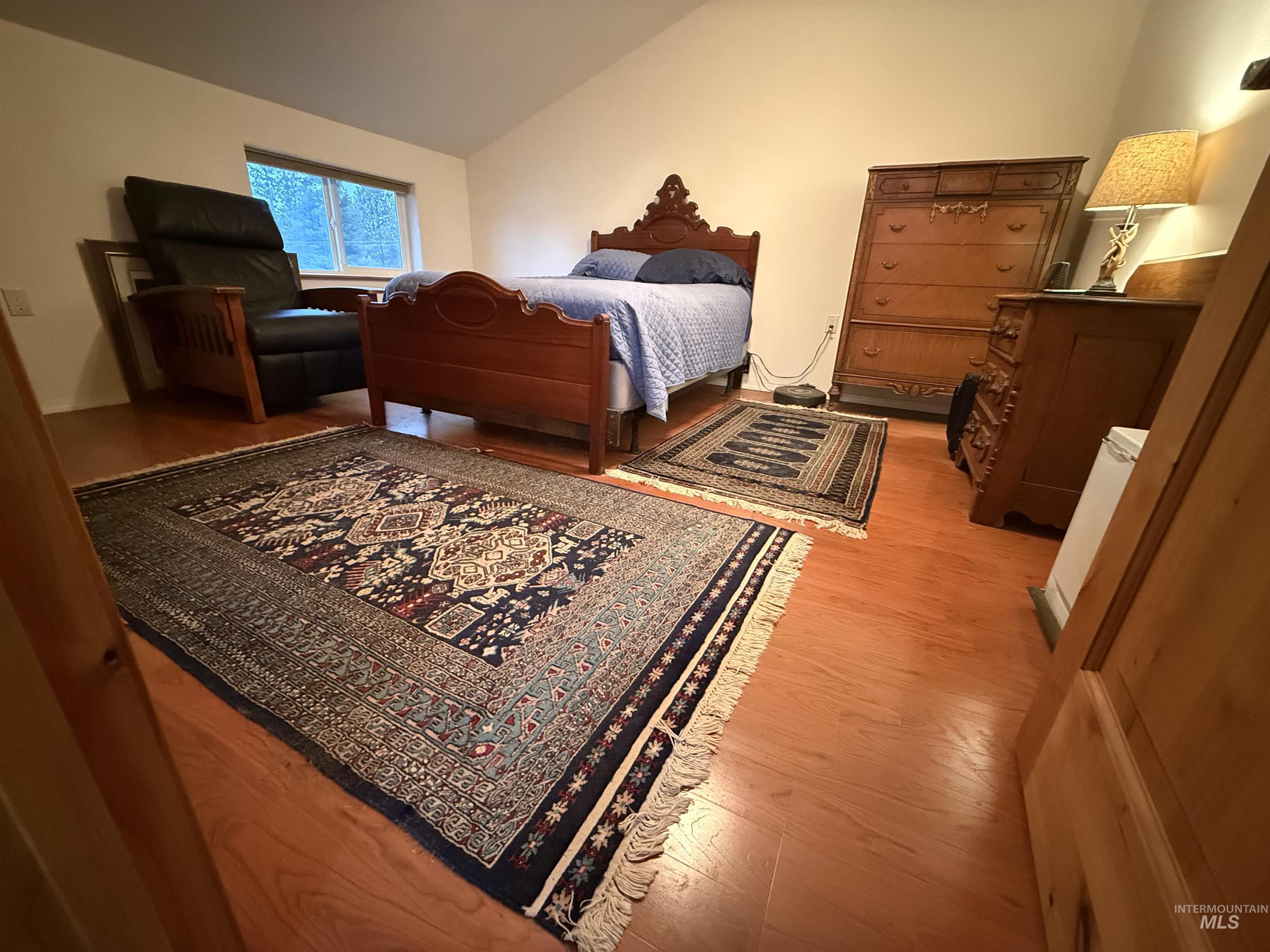 Bedroom with vaulted ceiling and light wood-style floors