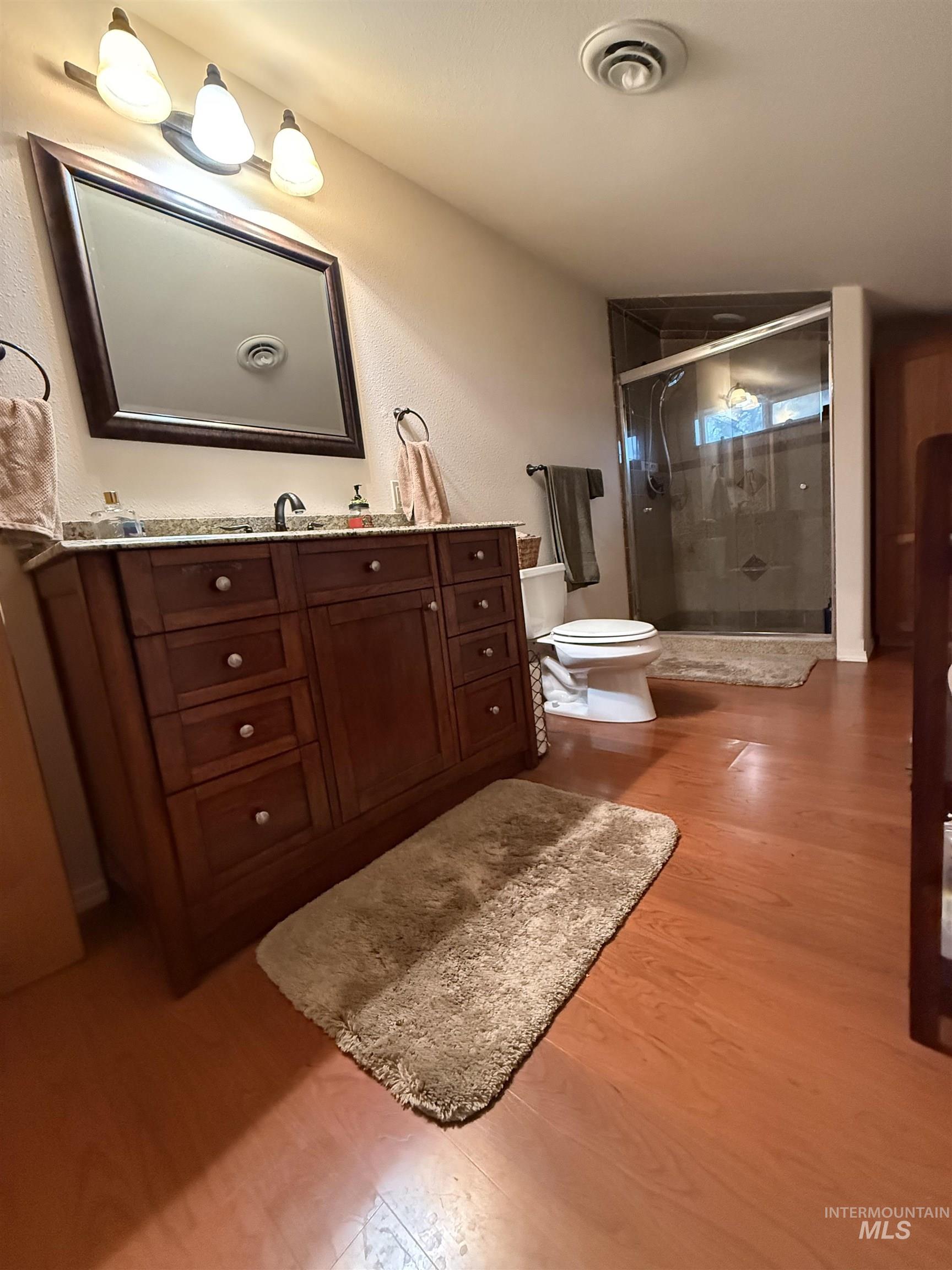 Bathroom with vanity, a stall shower, and light wood-style flooring