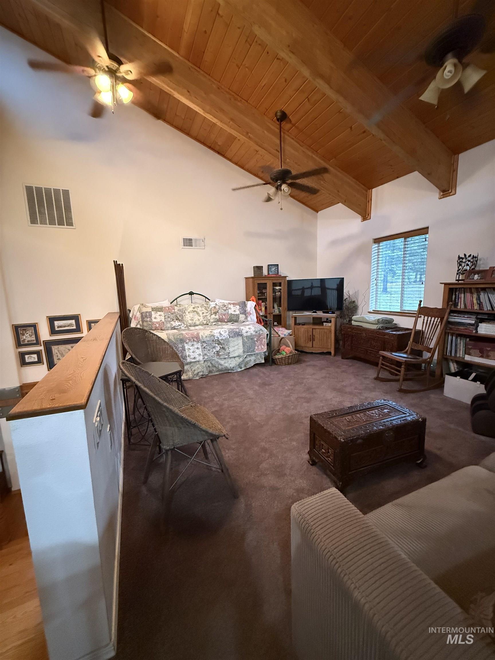 Living area featuring wooden ceiling, ceiling fan, and dark carpet