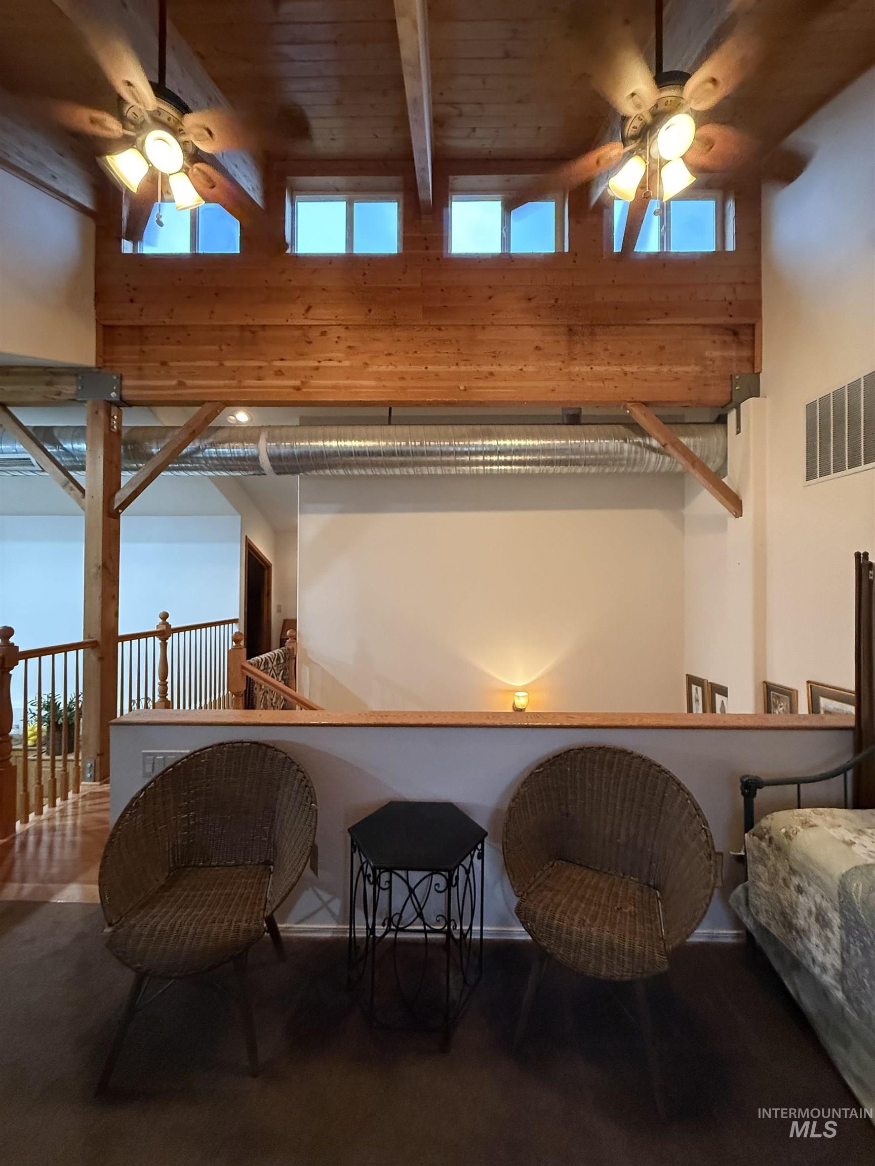 Sitting room with a ceiling fan, a high ceiling, beamed ceiling, and plenty of natural light