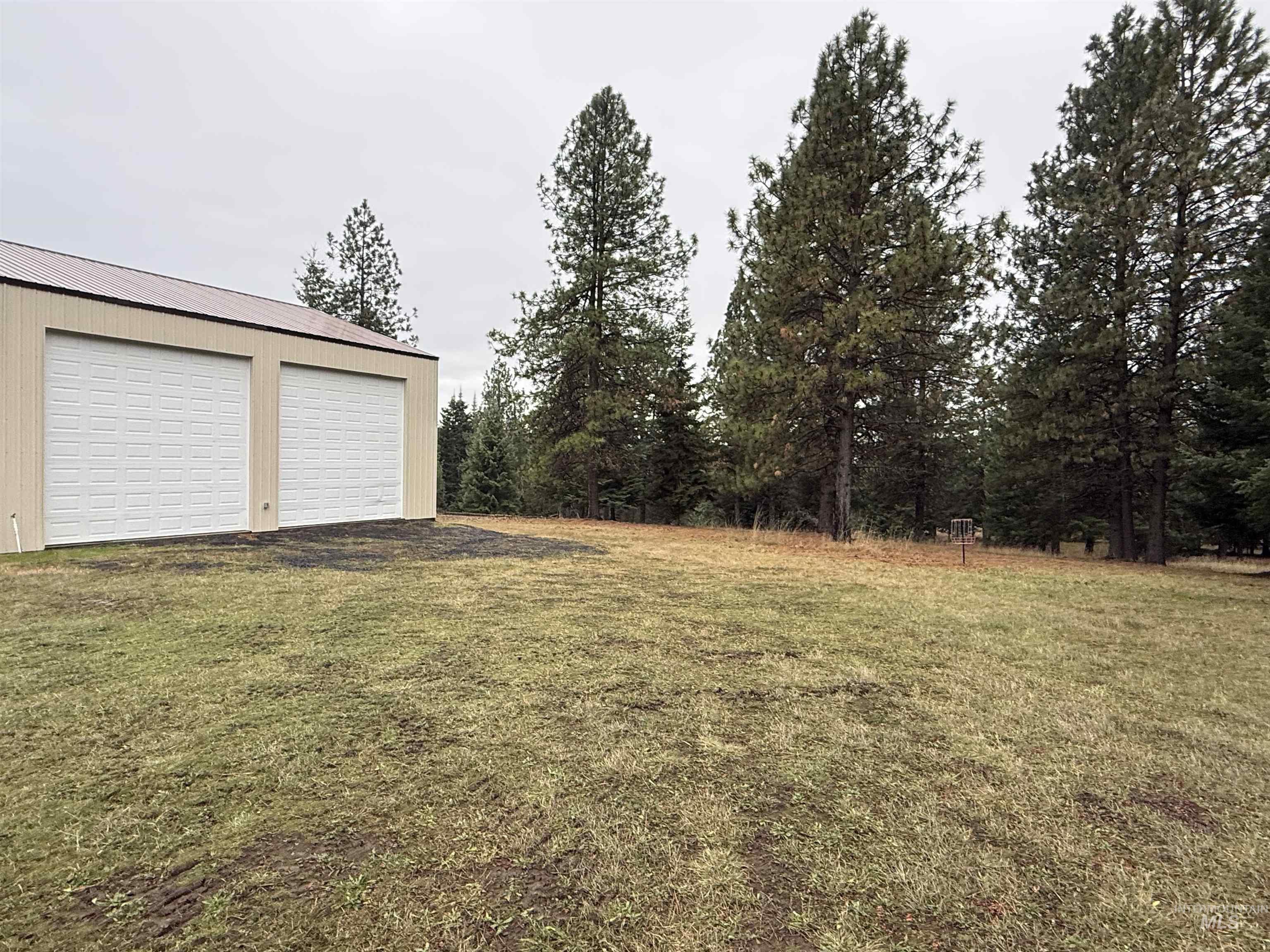 View of green lawn featuring an outbuilding and a garage