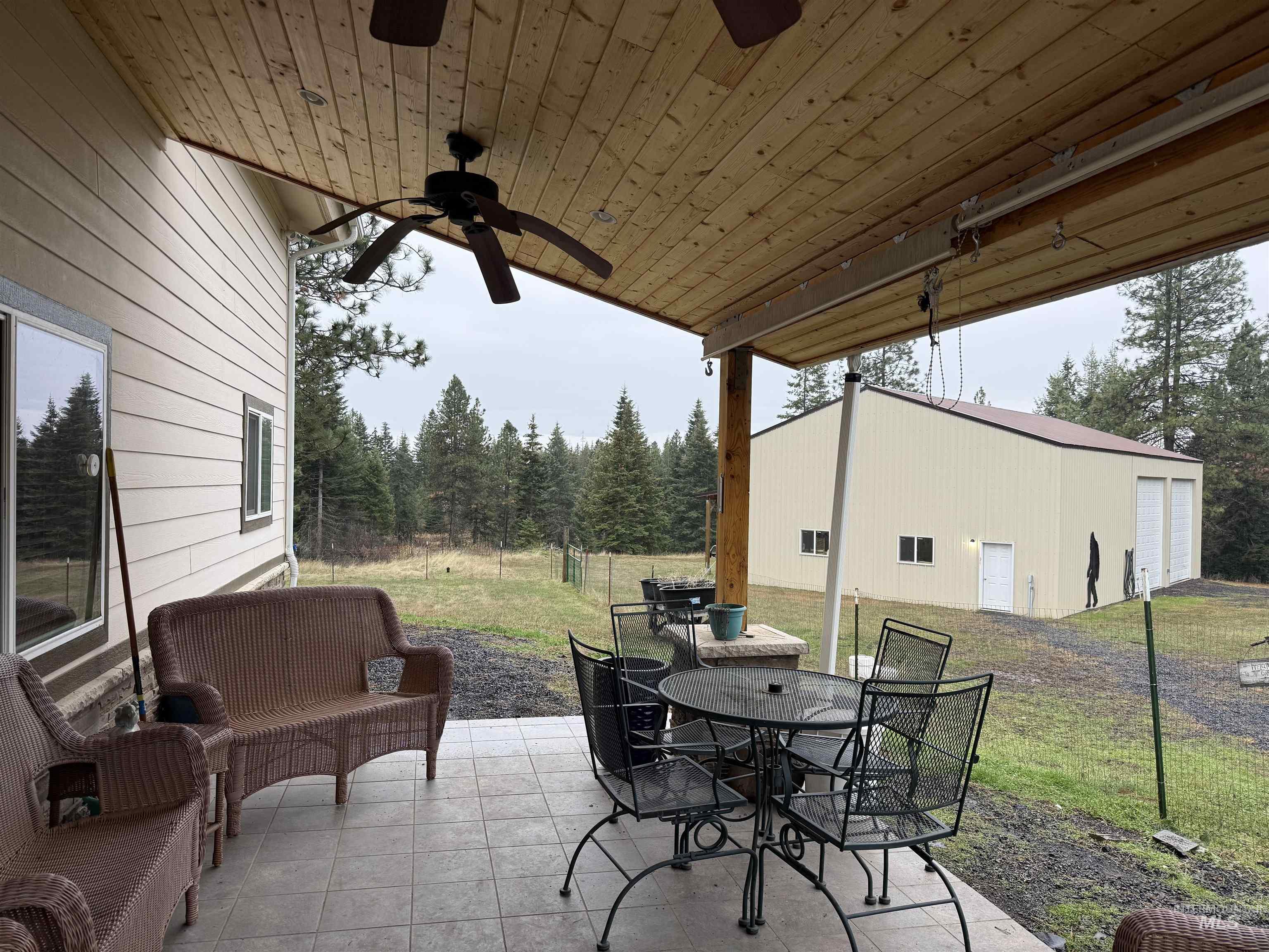 View of patio with outdoor dining area, an outdoor structure, and ceiling fan