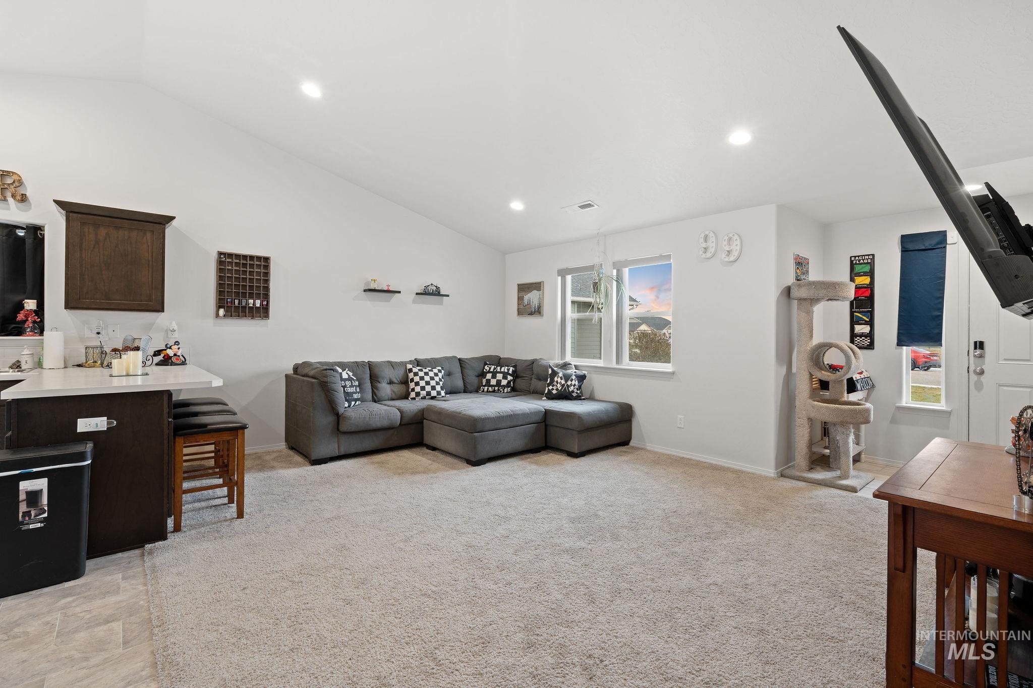 Living area featuring lofted ceiling, light colored carpet, and recessed lighting