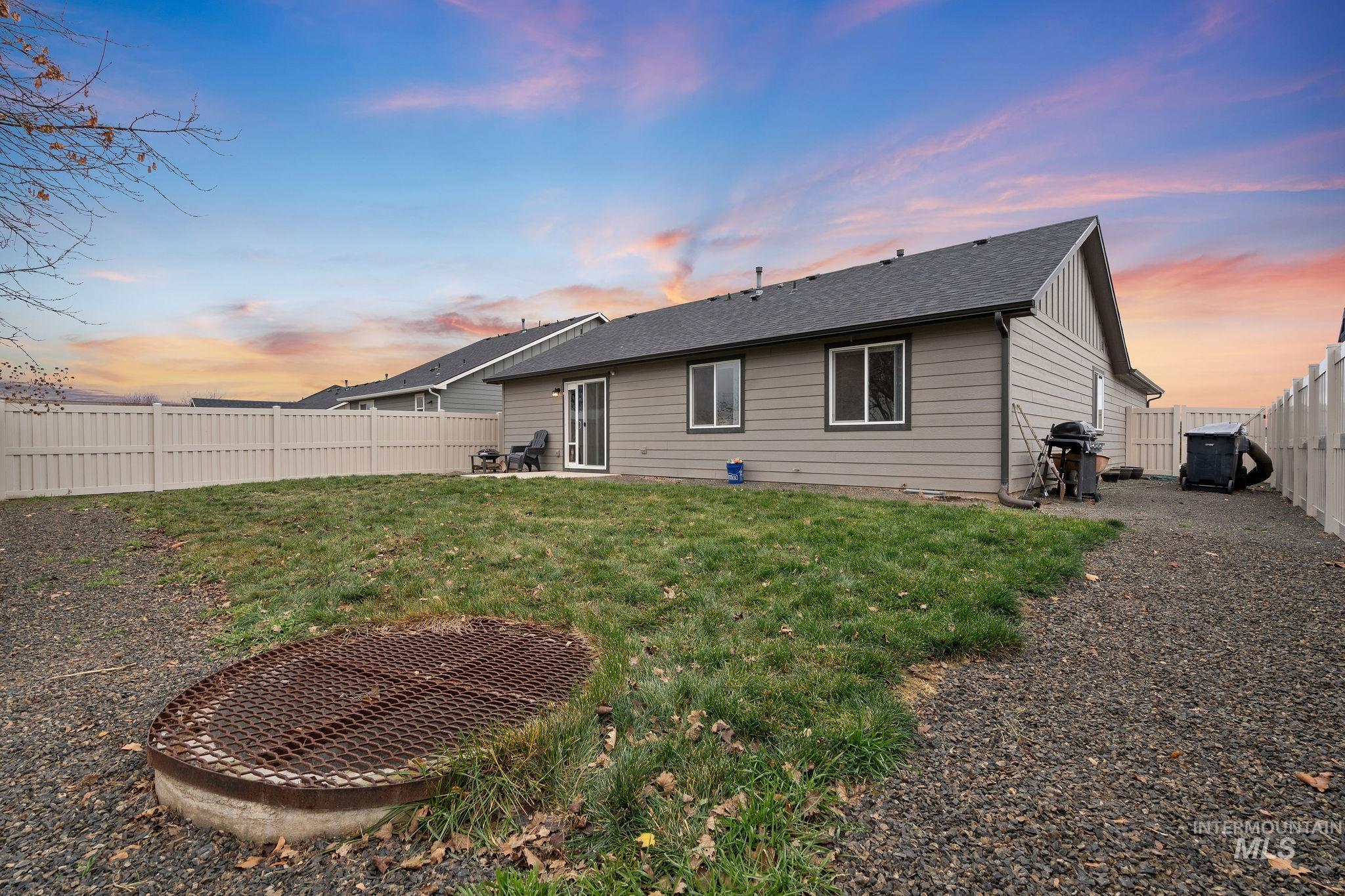 Back of property at dusk with a fenced backyard, a patio area, and roof with shingles