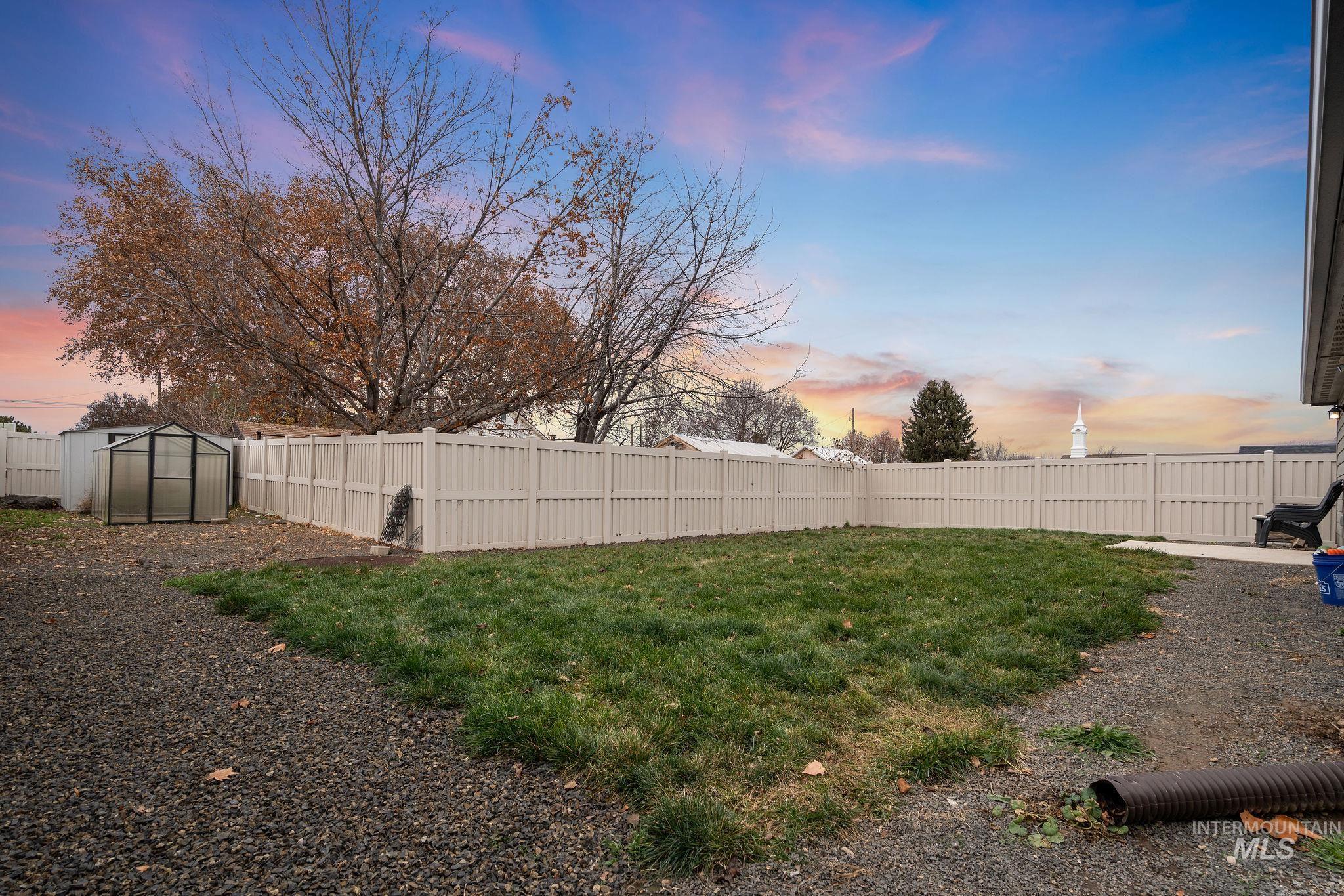 Yard at dusk with a fenced backyard and an outbuilding