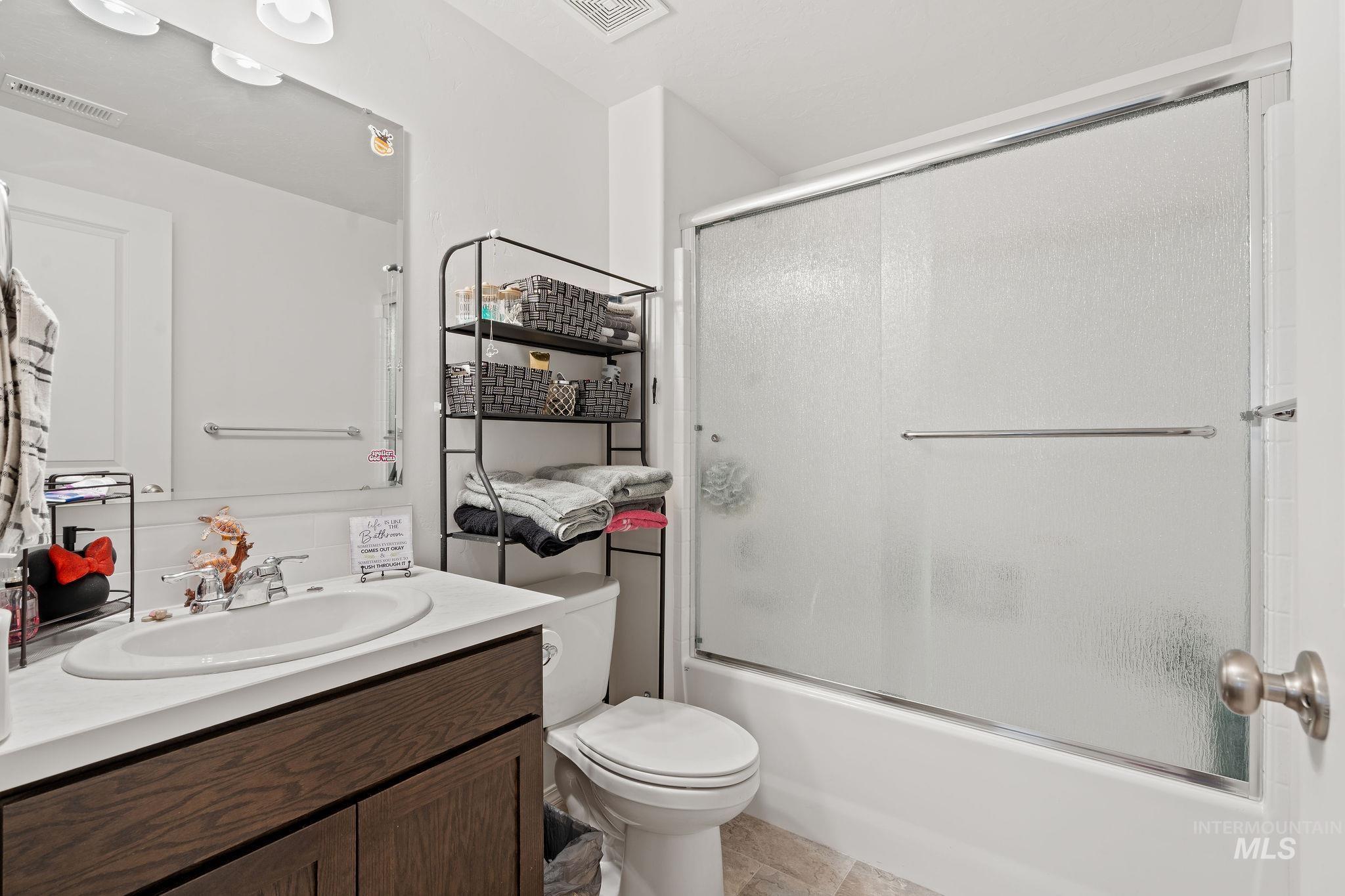 Bathroom featuring vanity and bath / shower combo with glass door