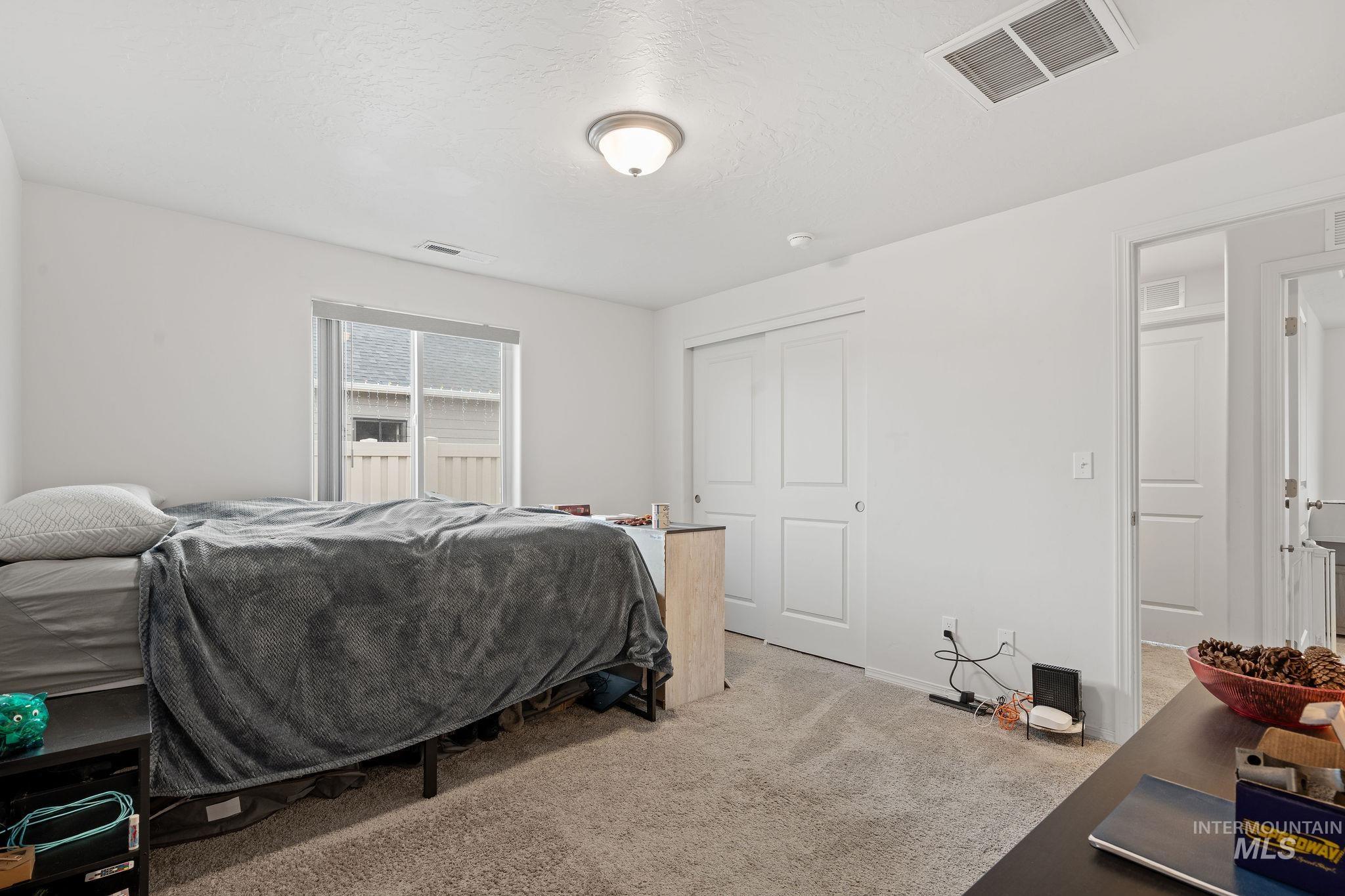 Bedroom featuring light carpet, a textured ceiling, and a closet