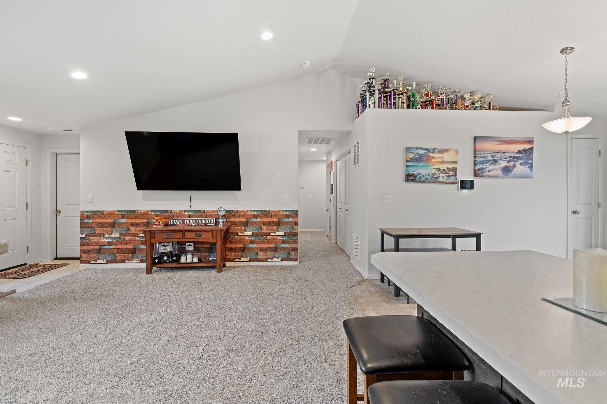 Living area featuring lofted ceiling, light carpet, and recessed lighting