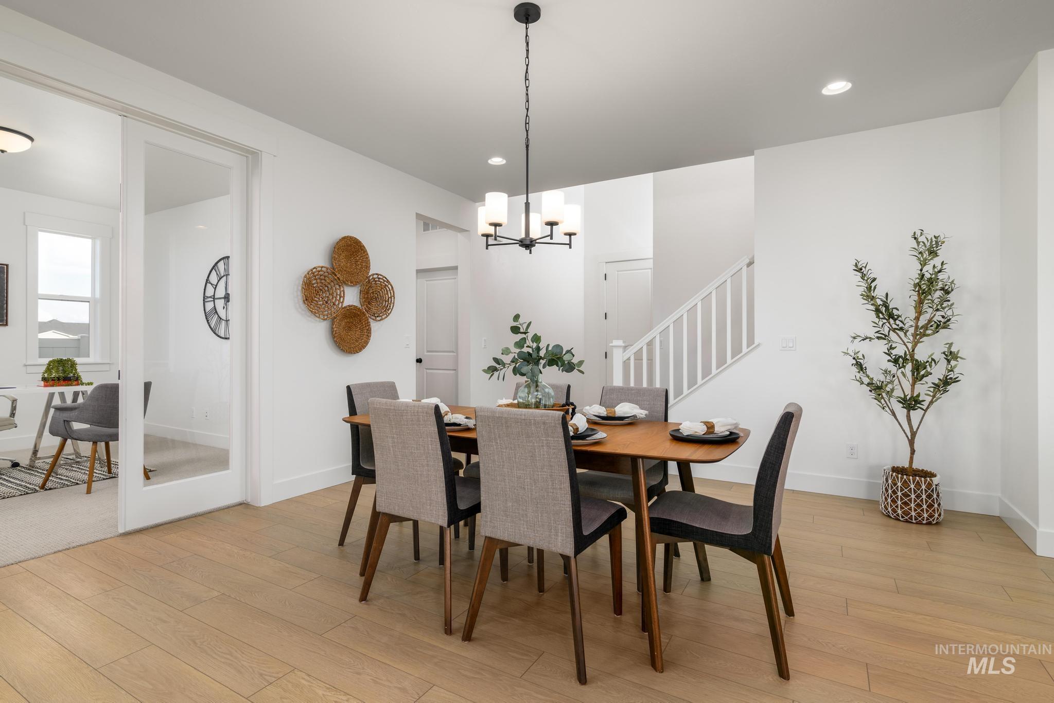 Dining area featuring stairs, light wood-type flooring, a chandelier, and recessed lighting