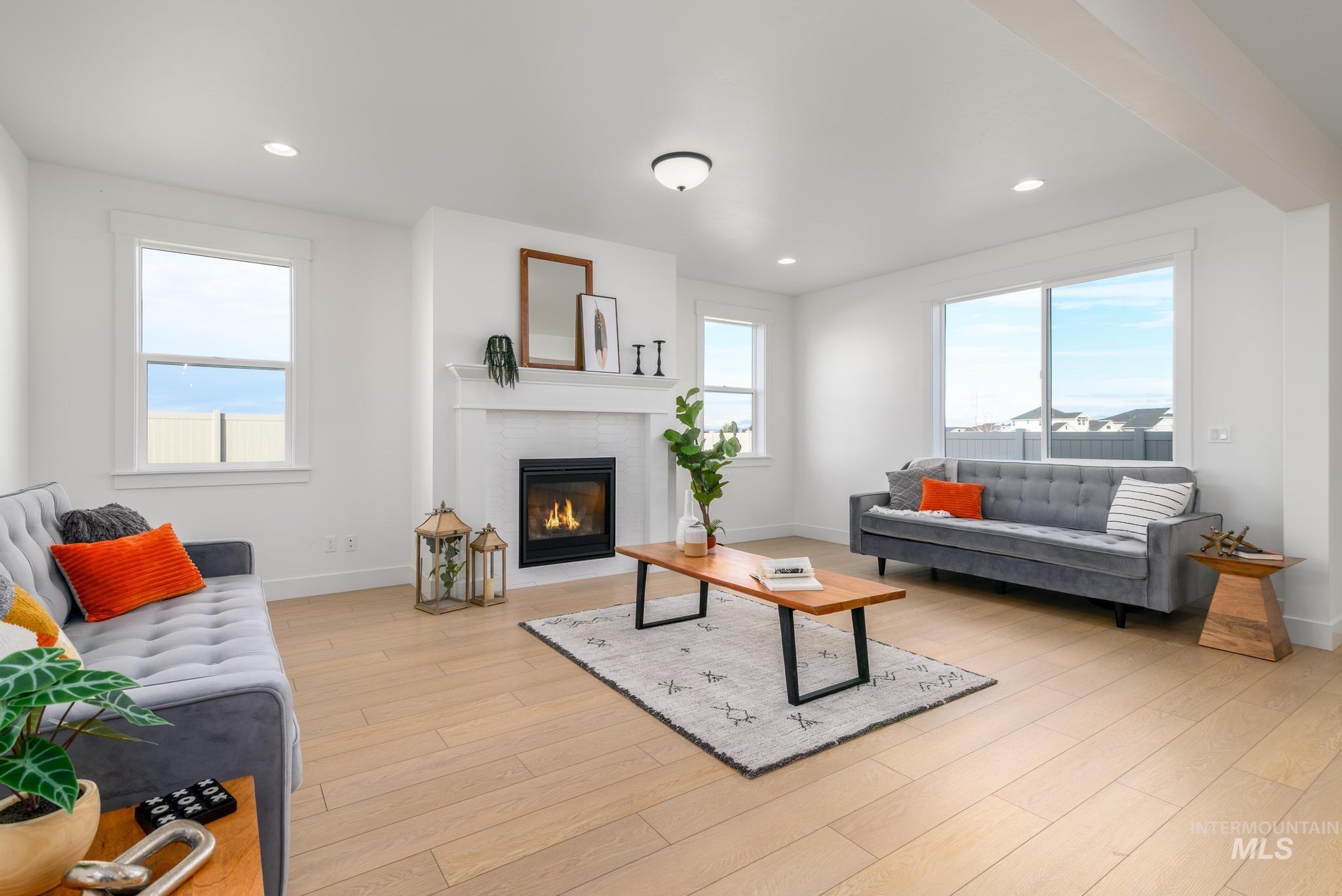 Living area with recessed lighting, a glass covered fireplace, and light wood-style flooring
