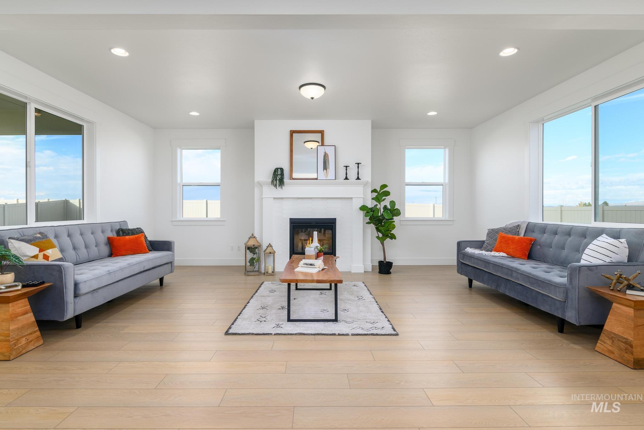 Living room with plenty of natural light, a glass covered fireplace, recessed lighting, and light wood-style floors