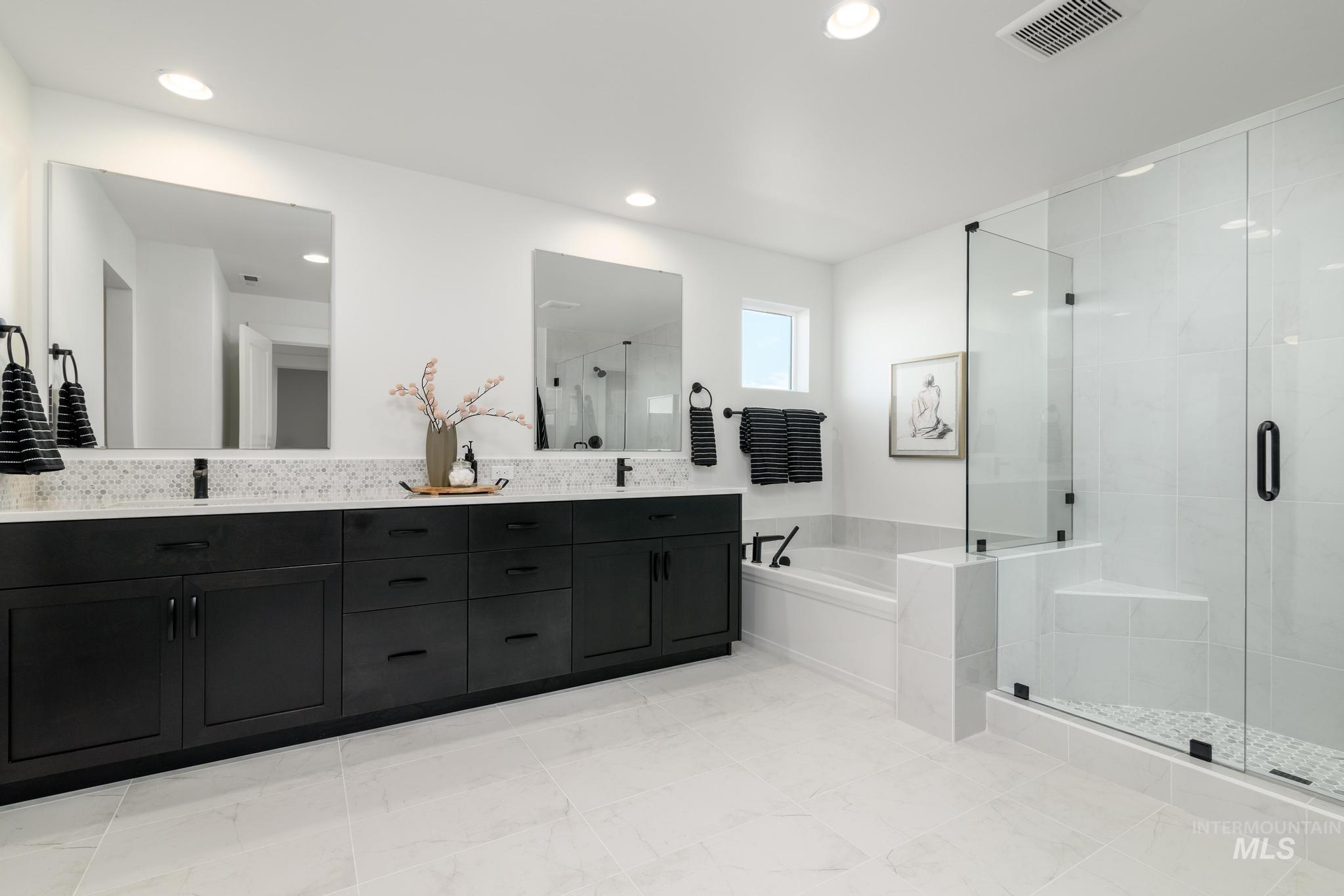 Bathroom featuring a garden tub, double vanity, and a stall shower