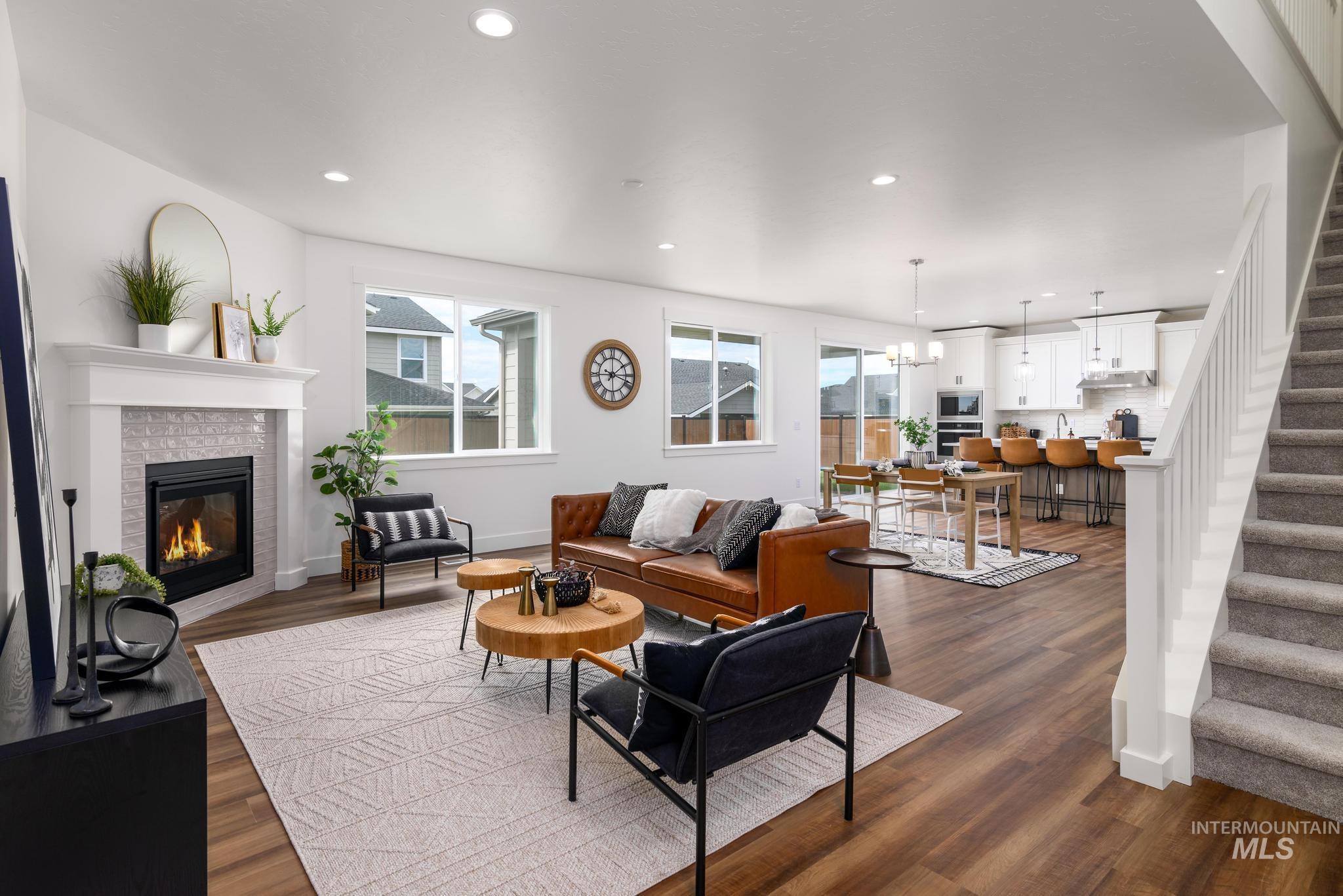 Living area with stairs, recessed lighting, dark wood-type flooring, a chandelier, and a glass covered fireplace