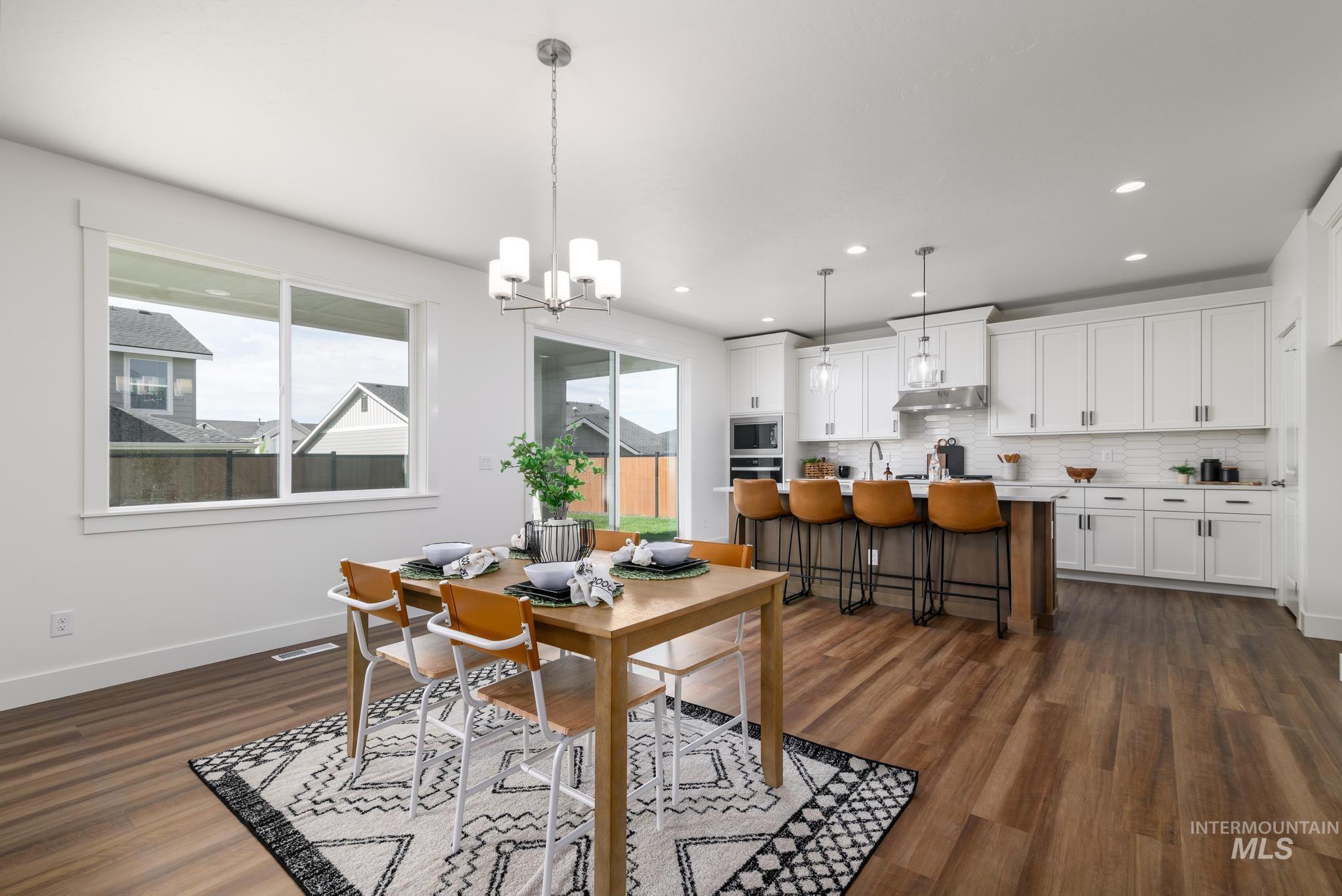 Dining space featuring a chandelier, dark wood-style floors, and recessed lighting