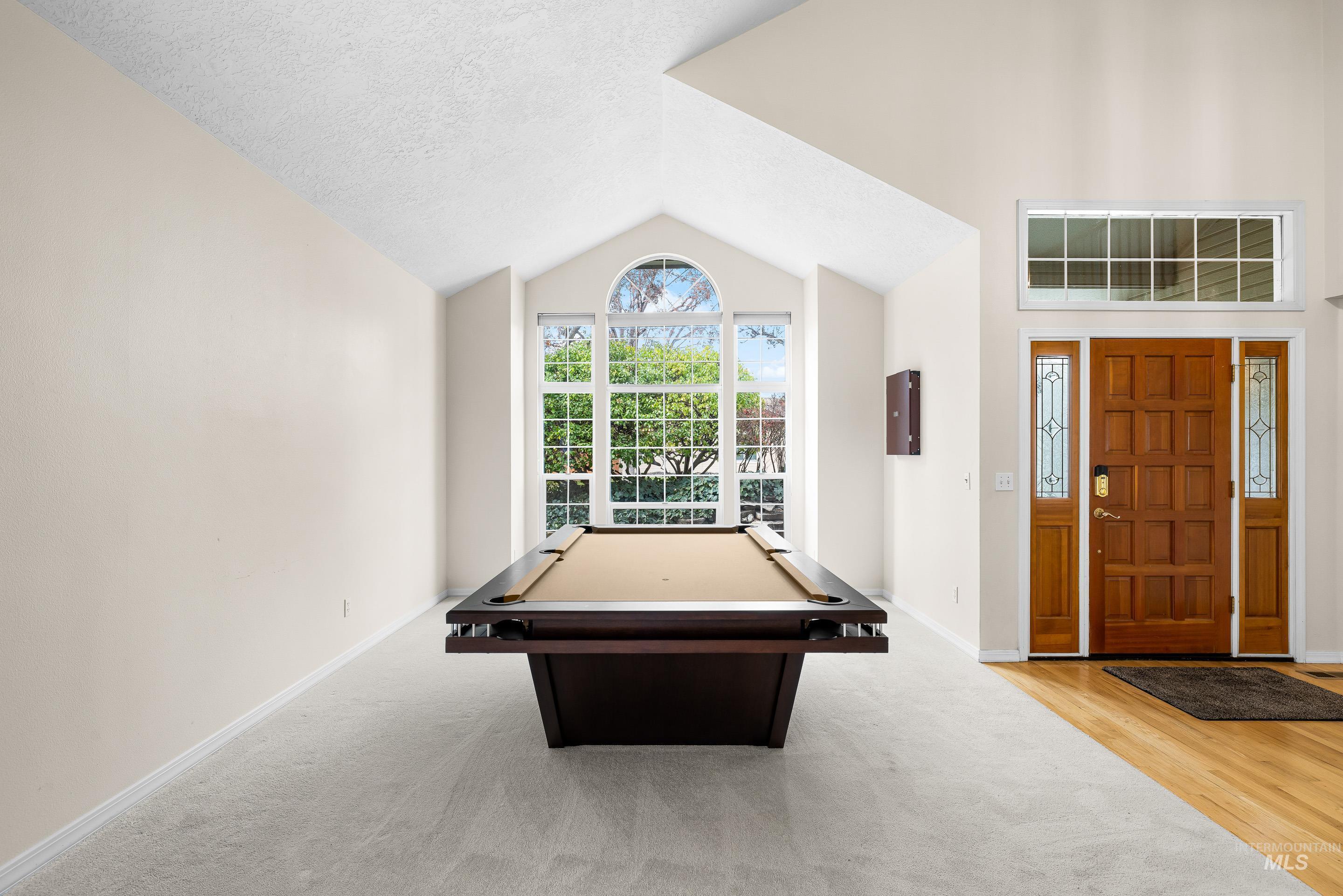 Game room with billiards table, vaulted ceiling, a textured ceiling, and light colored carpet
